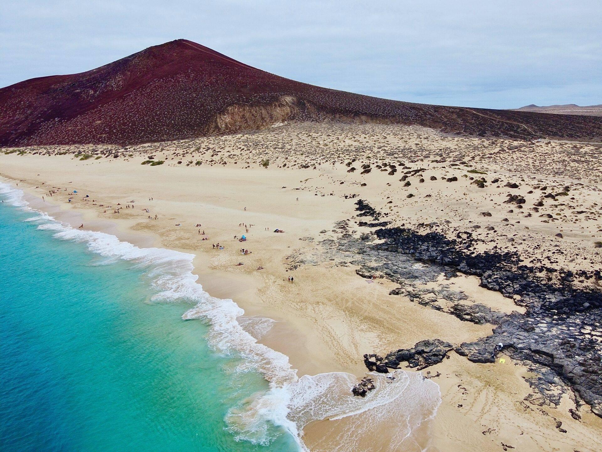 Volcanic coastline of the Canary Islands under a clear blue sky, a traveller out for a walk