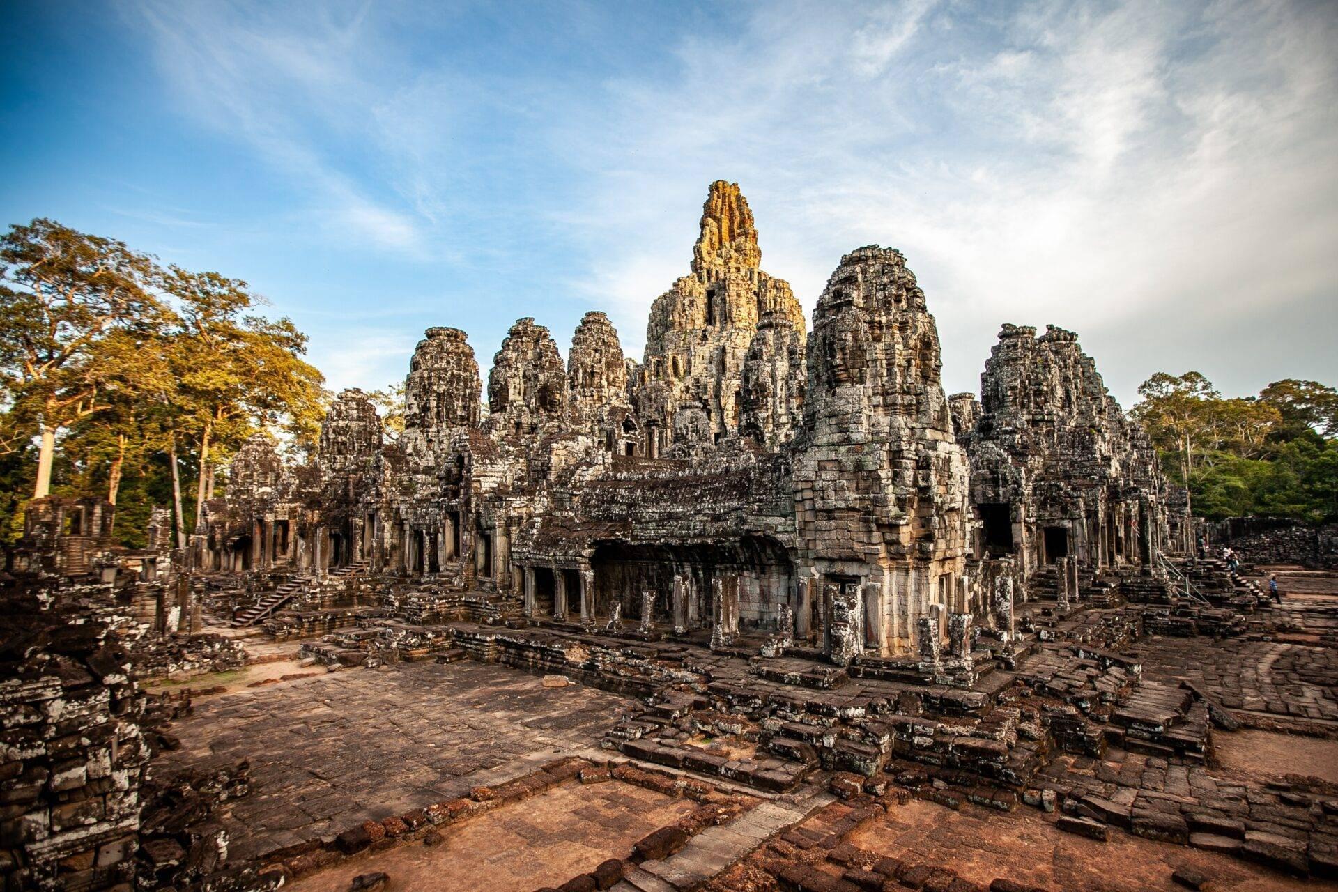 Ruines de temple en pierre avec tours sculptées entourées de végétation tropicale et ciel dégagé