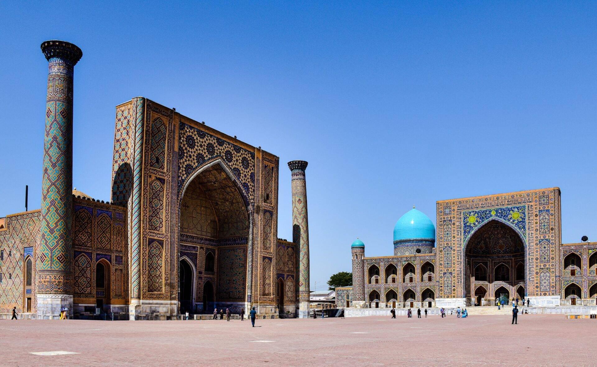 Grand square flanked by richly decorated Islamic buildings with turquoise domes and colourful geometric facades