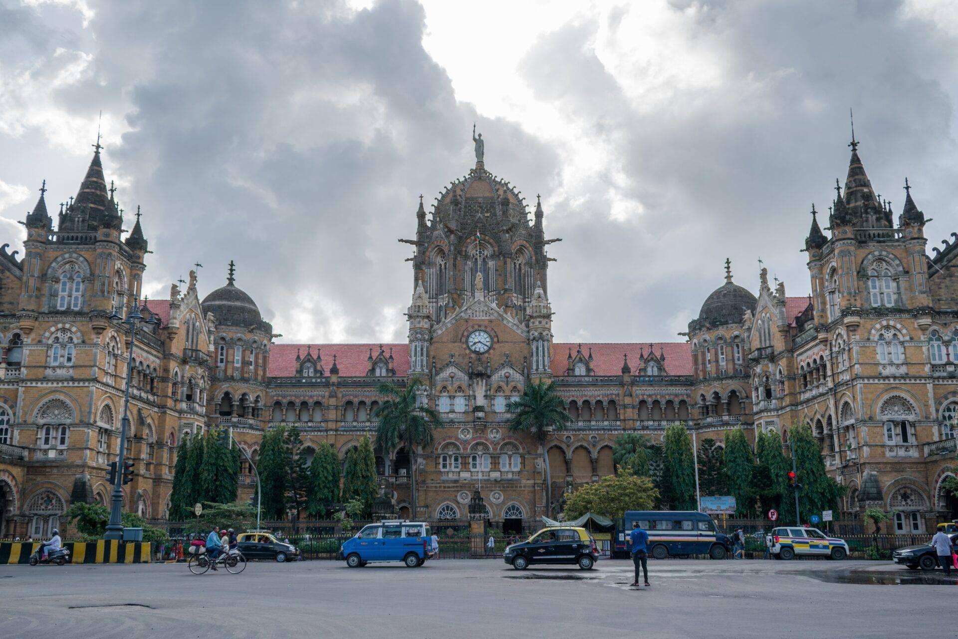 Historic brick railway station with three grand towers and a forecourt filled with taxis and vehicles