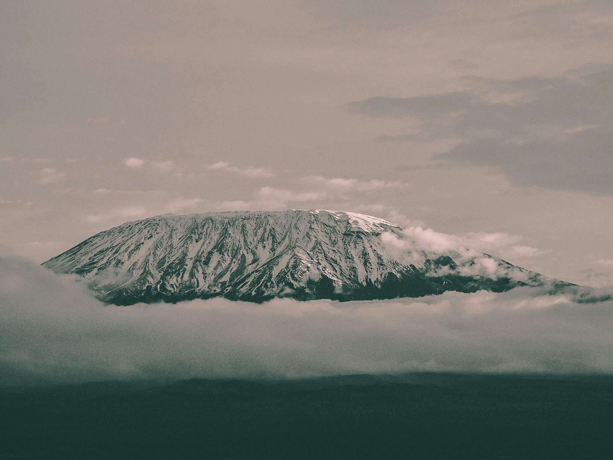 Un volcan enneigé émergeant des nuages dans une atmosphère brumeuse et mystérieuse