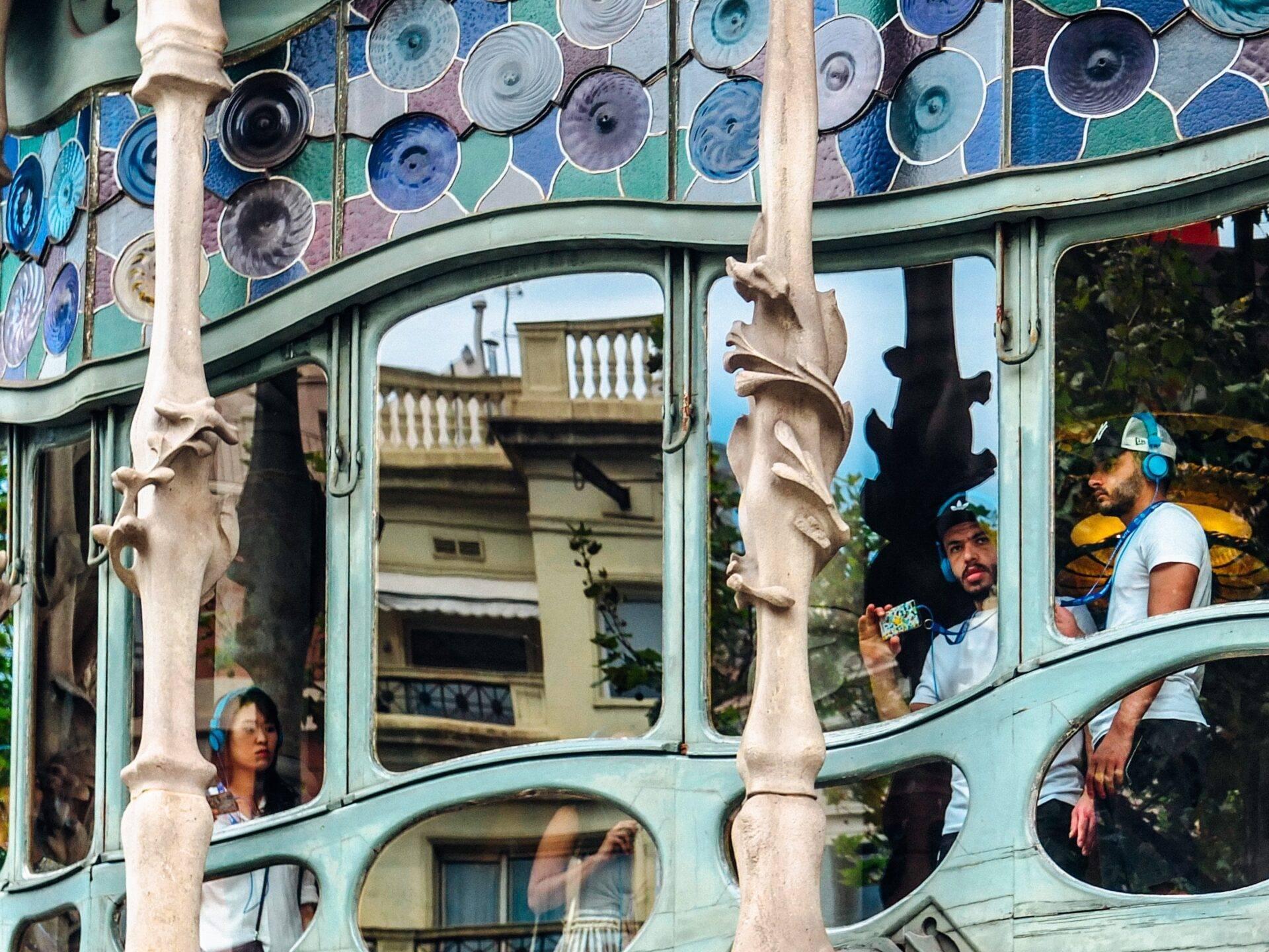 Façade colorée avec assiettes décoratives bleues et turquoises, reflets urbains dans les vitres courbes