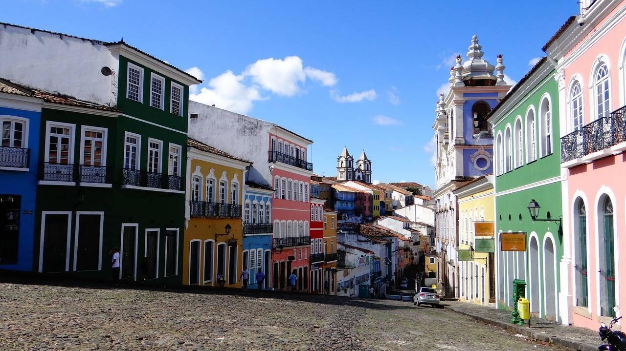 A historic cobbled street lined with colourful houses and colonial churches under a blue sky