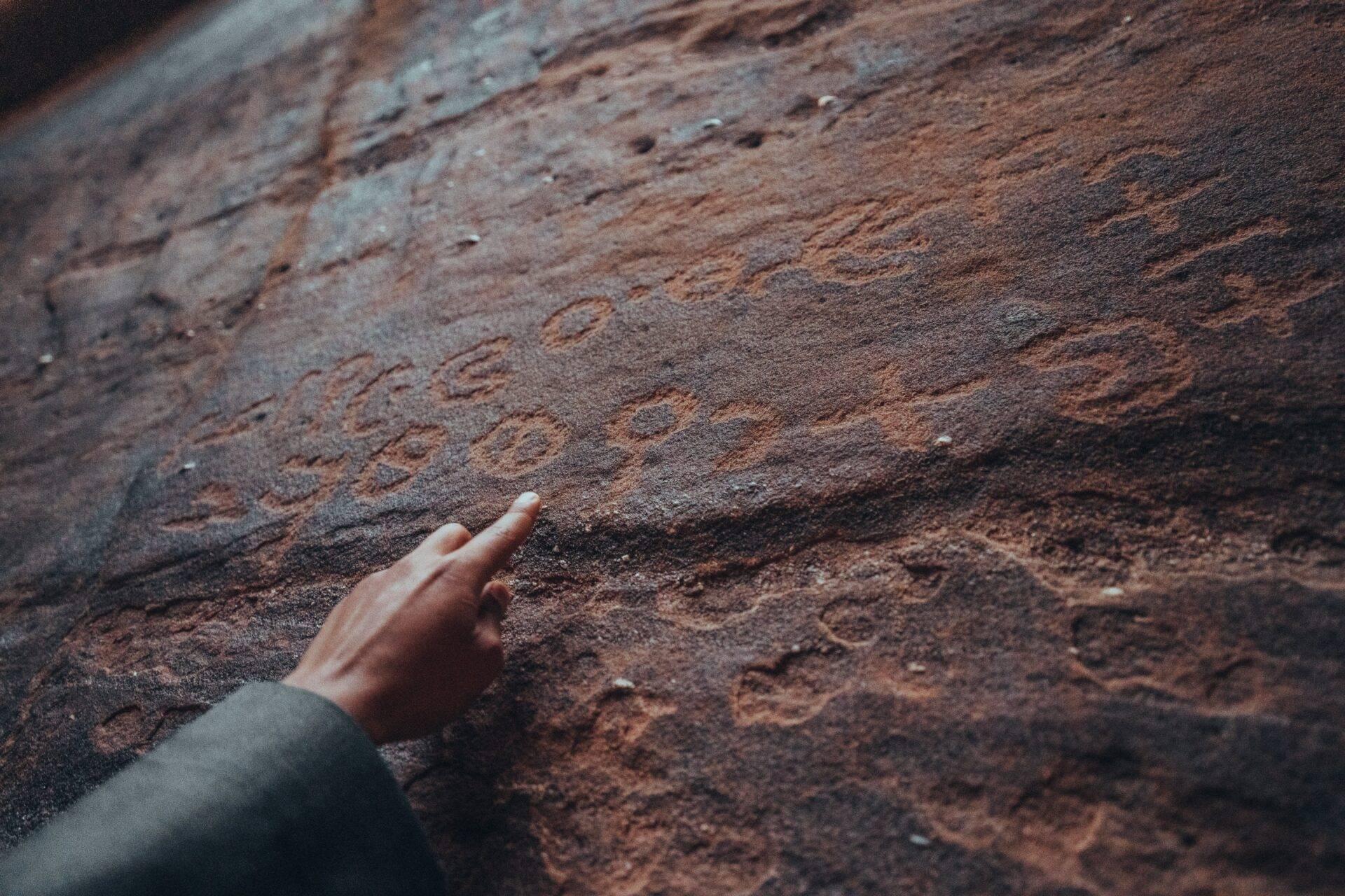 A child’s hand touching the rough surface of ancient reddish brickwork on a historic structure