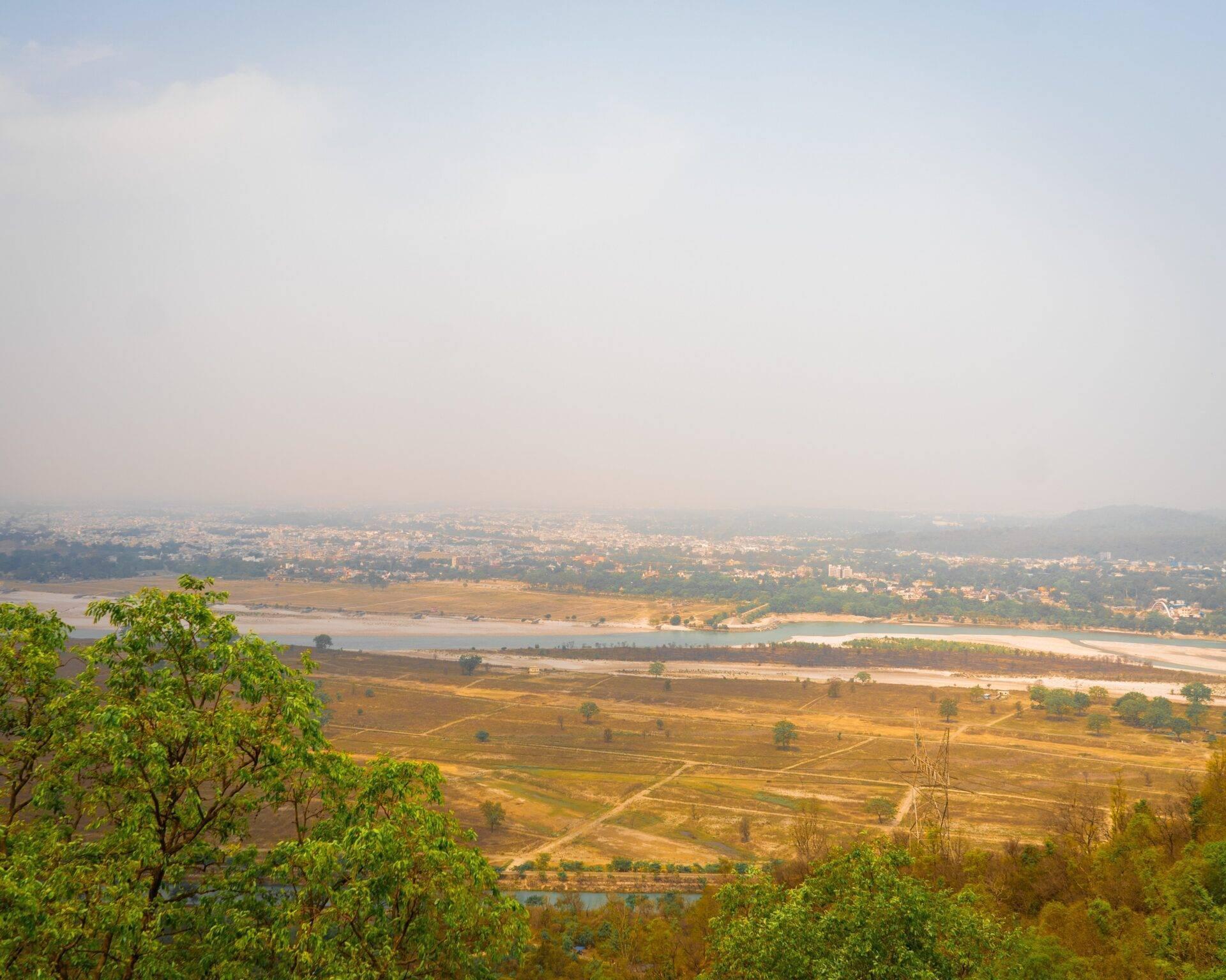 Panoramic view of a river valley with rice fields, scattered villages and atmospheric mist in the background