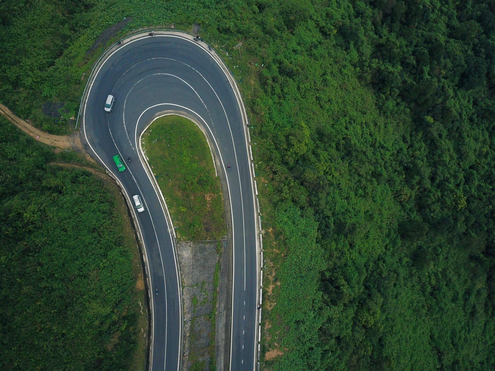 Vue aérienne d’une route sinueuse en épingle à cheveux traversant une forêt dense et verdoyante