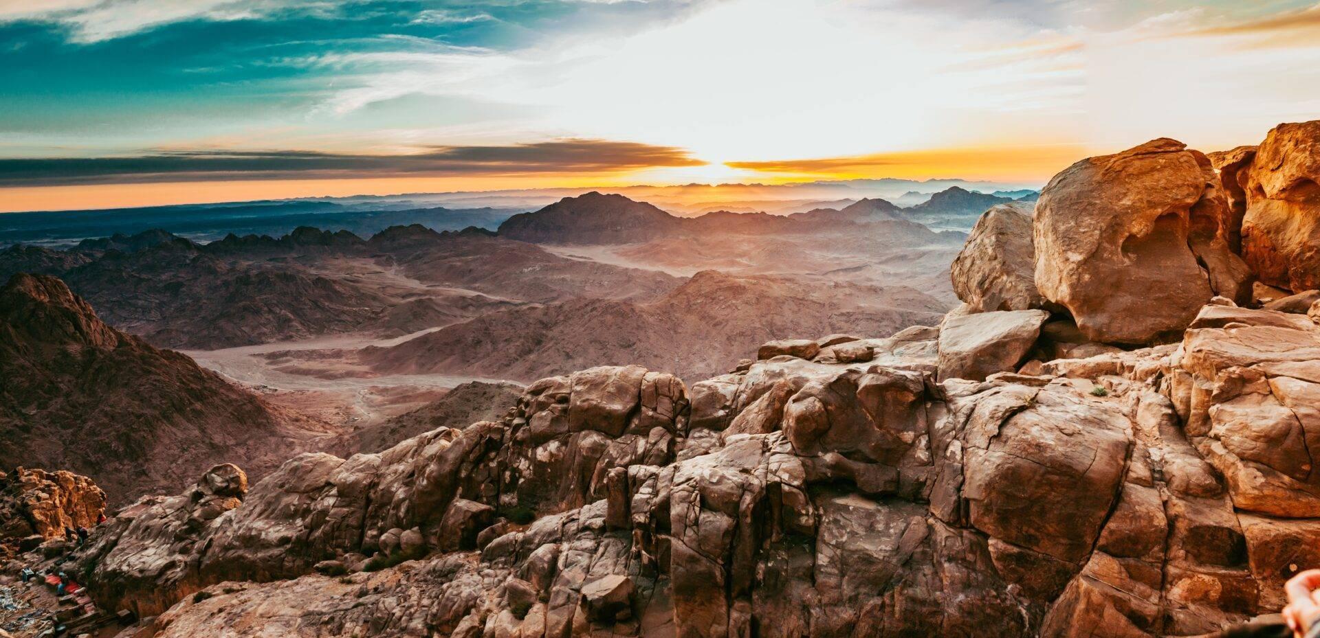 Panoramic view of a rocky mountain desert at sunset, with granite formations in the foreground