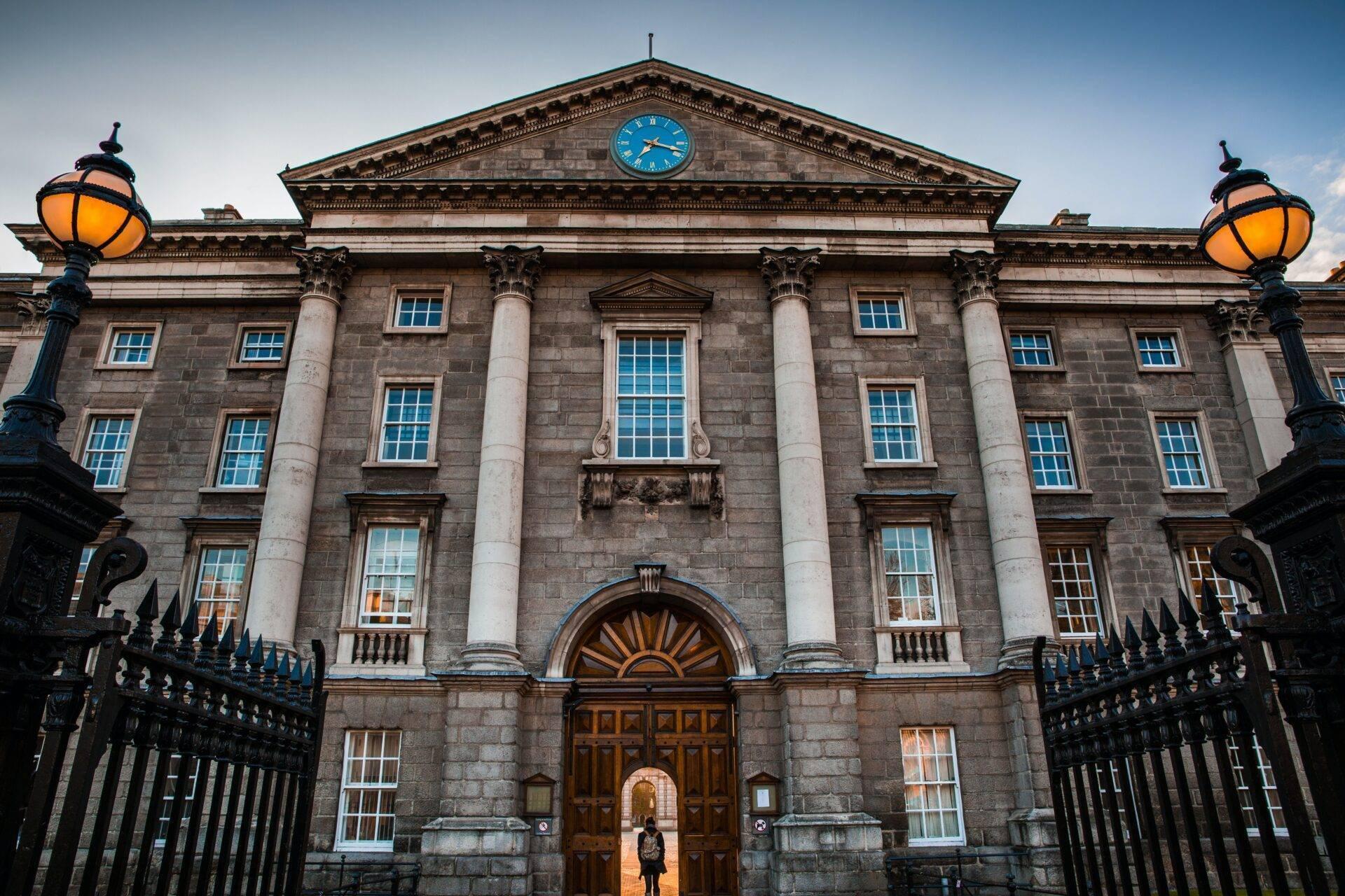 Majestic facade of a stone administrative building with a blue clock, white columns and gilded doors
