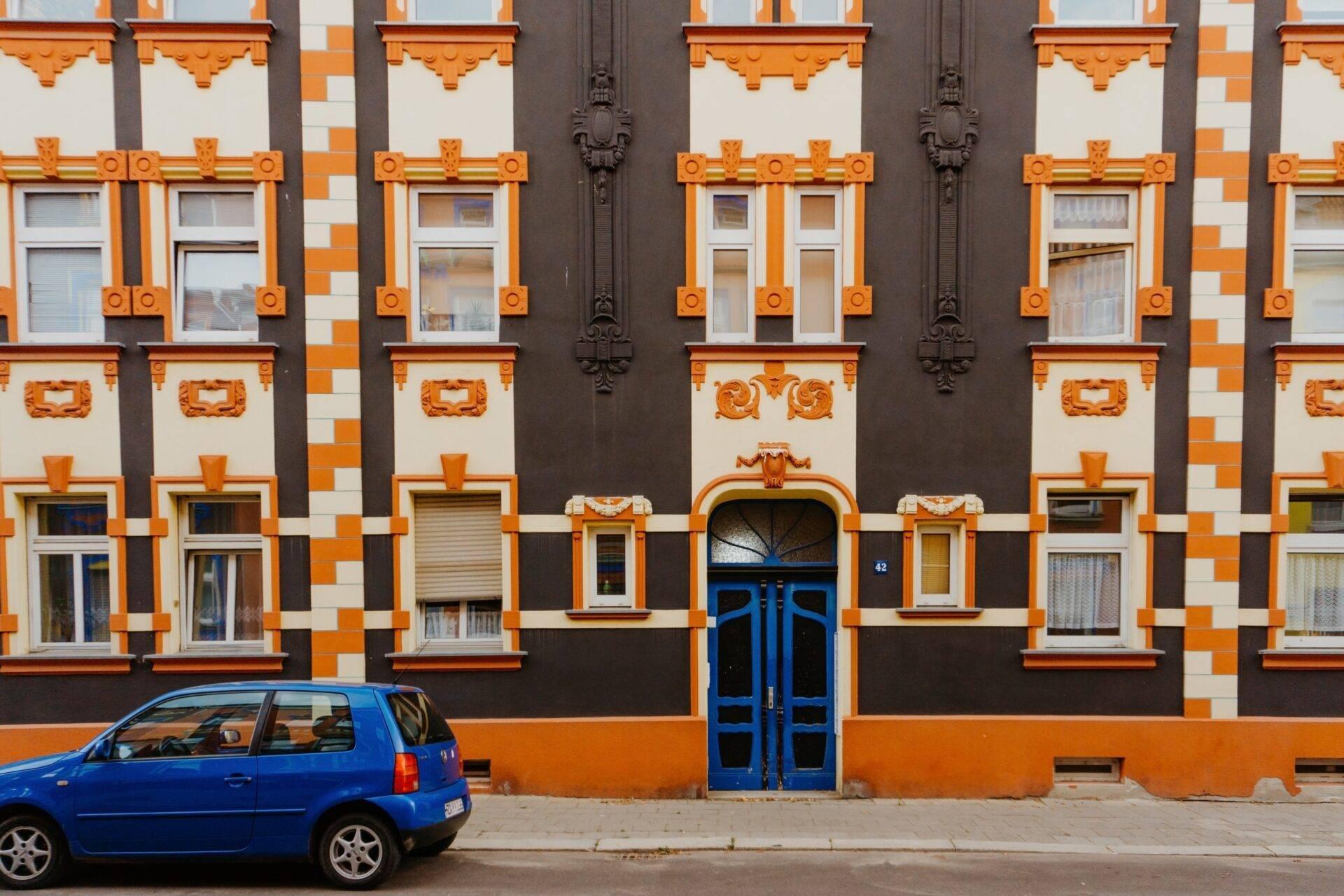 Colourful Art Deco building facade in orange and black with a blue car parked in front