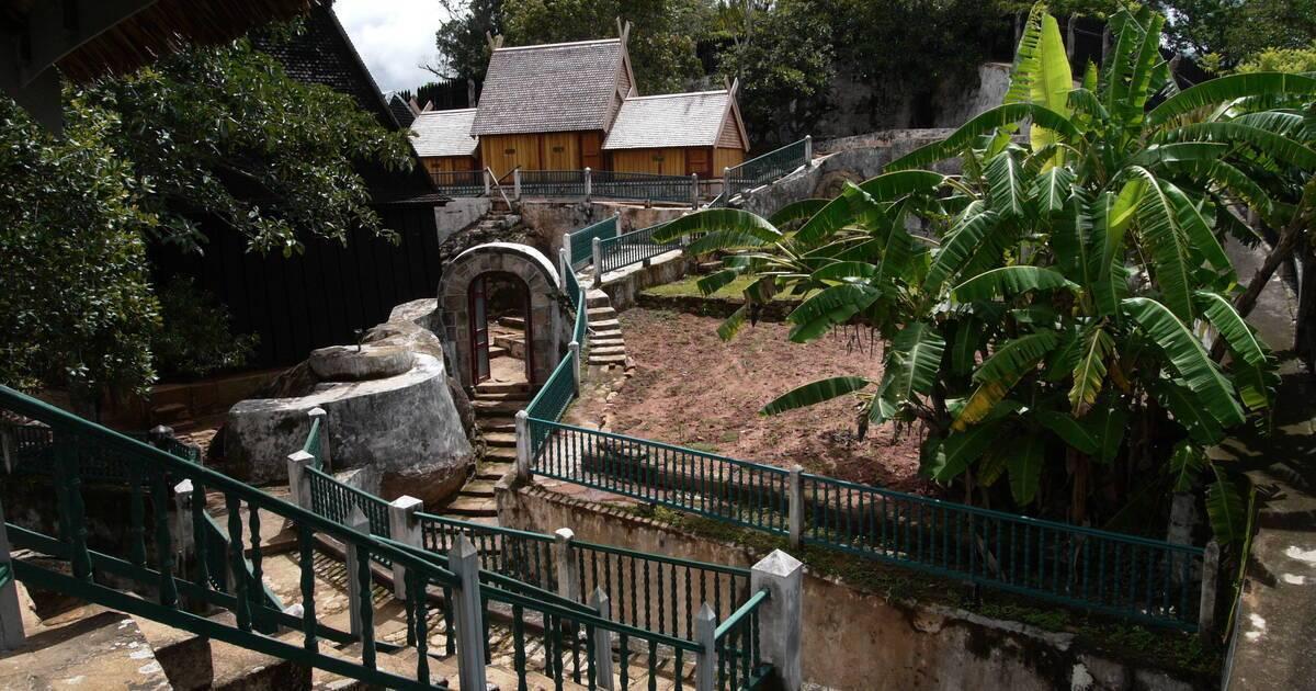 A tropical lodge with wooden buildings, stone steps, water features and lush surrounding vegetation