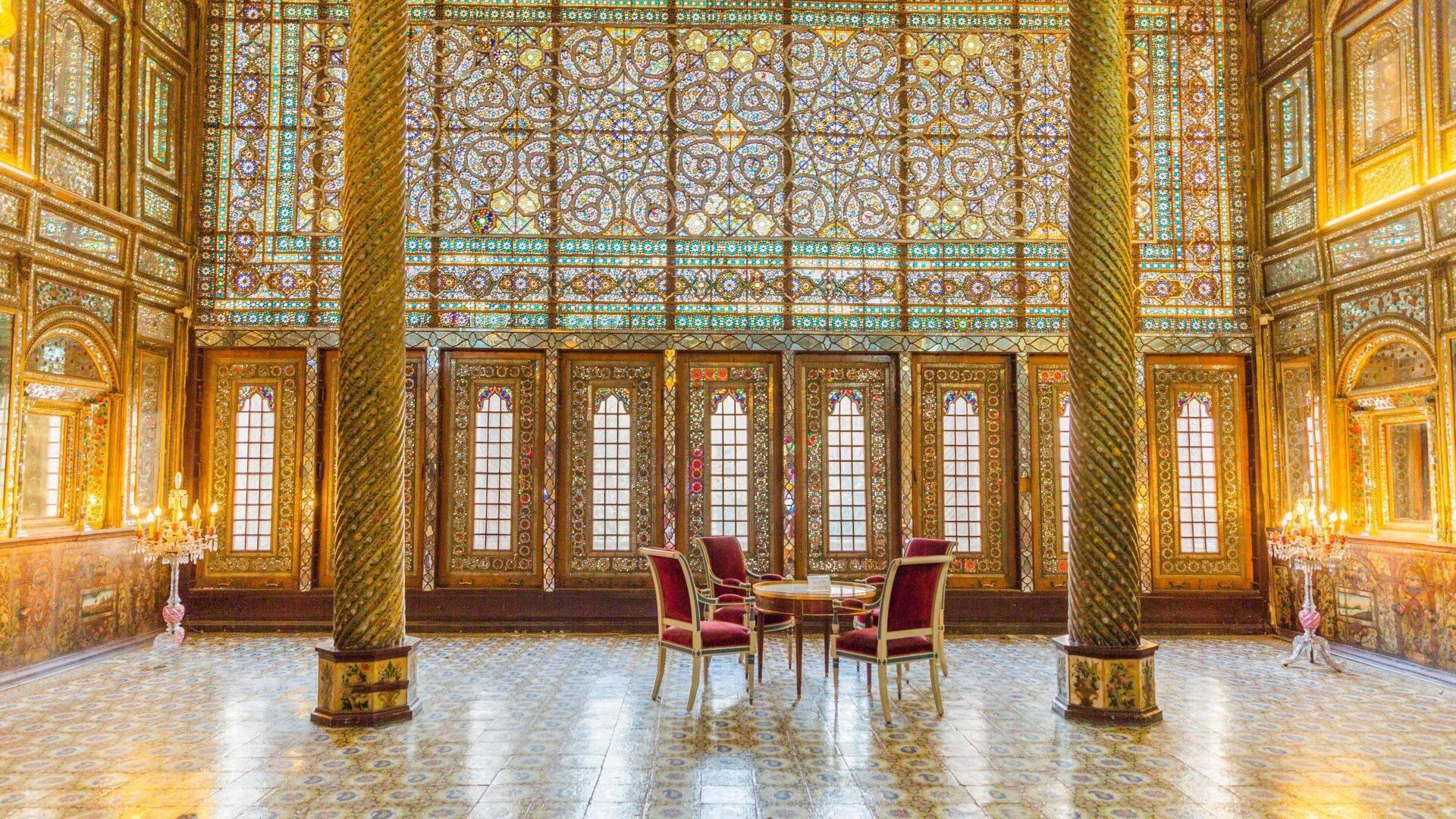 Room adorned with gilding and turquoise mosaics, with golden columns and red chairs