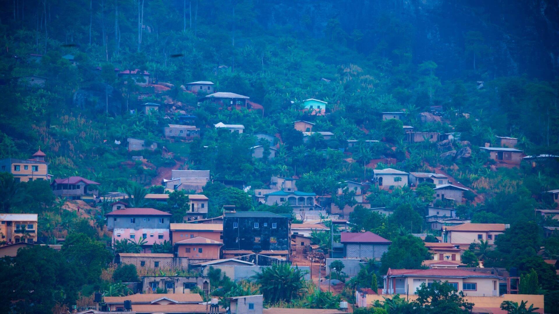 Vue aérienne d’un village montagneux avec maisons colorées dispersées parmi la végétation tropicale dense