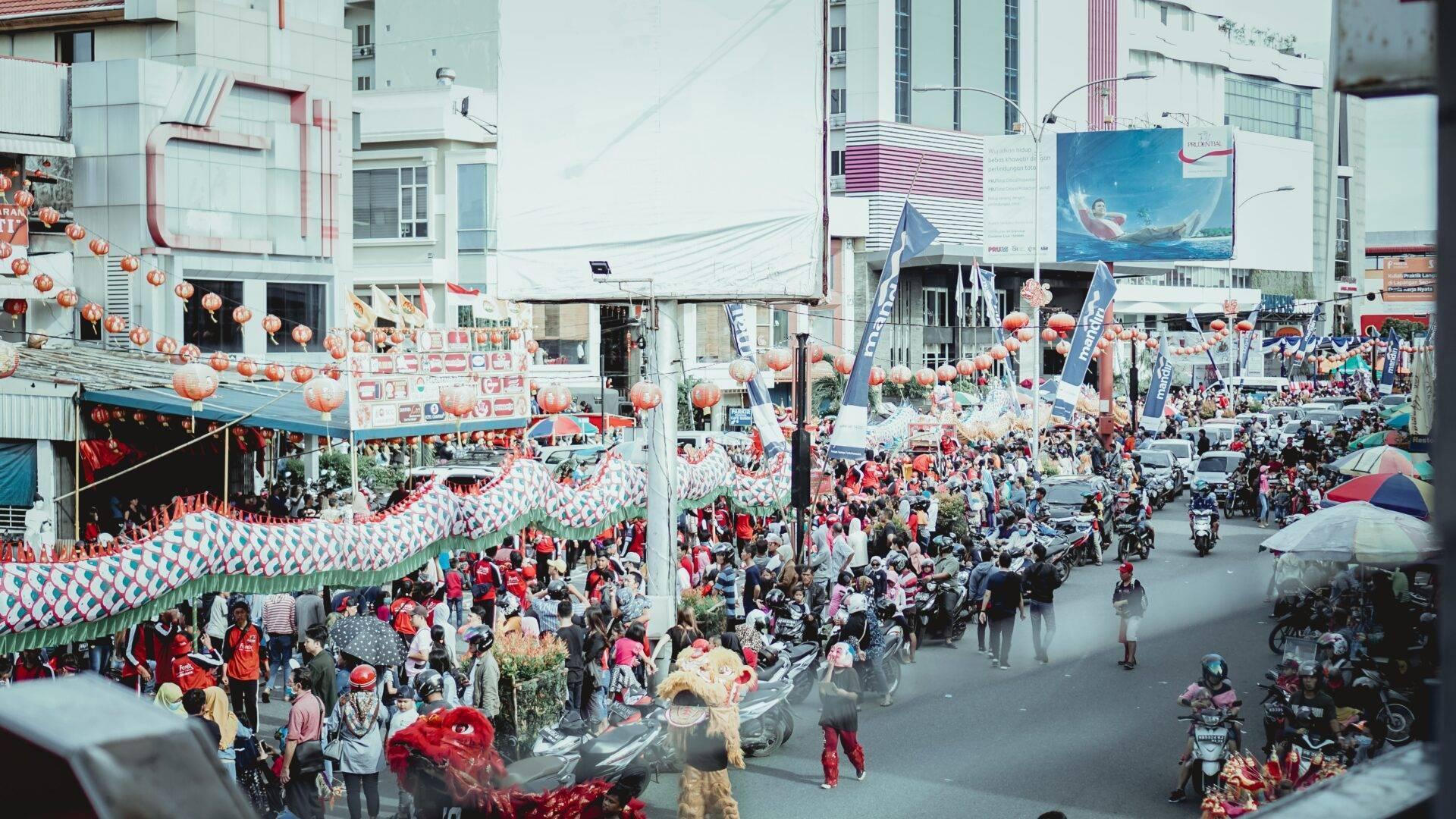 A busy urban street decorated with red lanterns and flags during a festive celebration in Indonesia