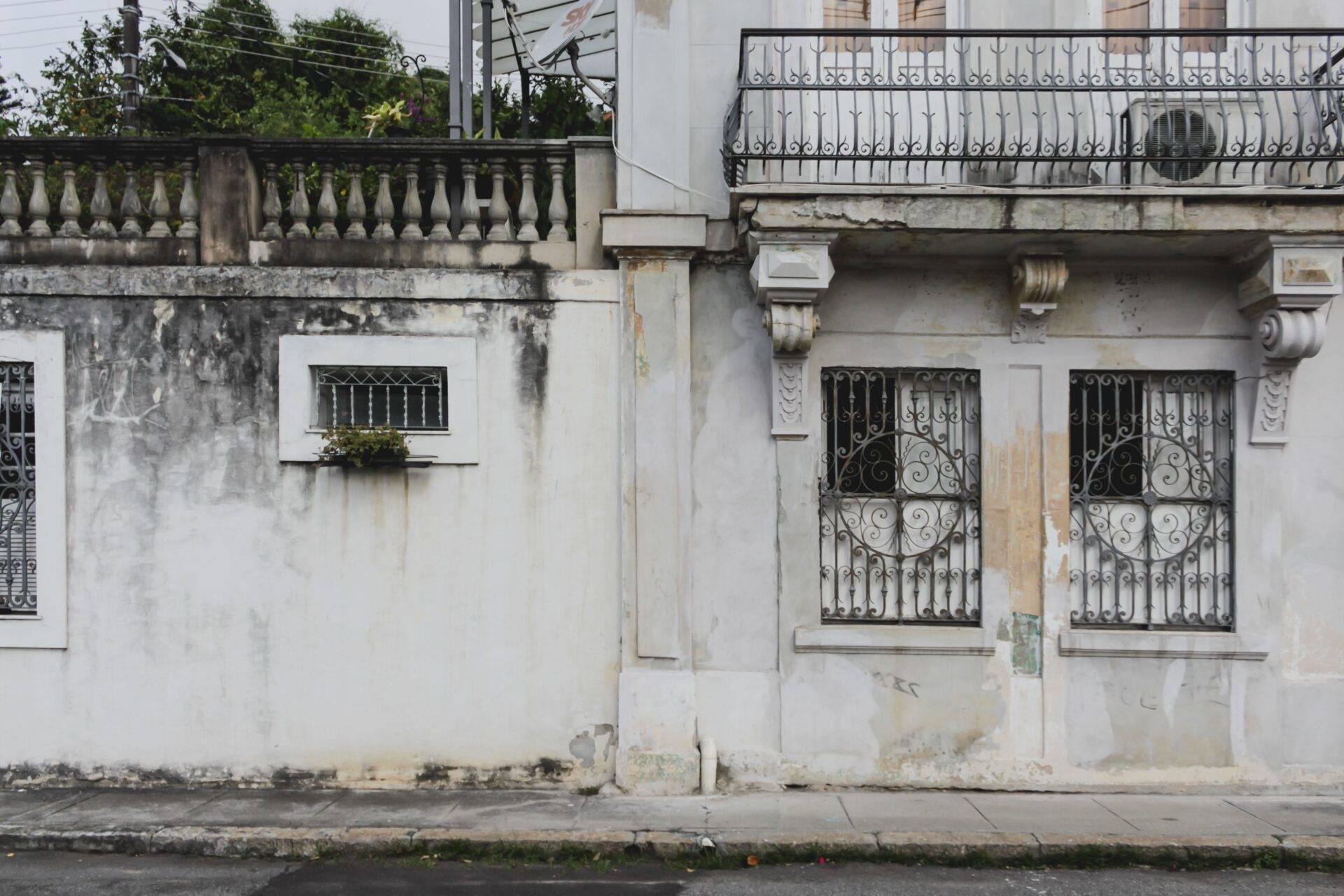Weathered colonial facade with an ornate iron balcony and decorative doors on a cobbled street in a historic Brazilian town