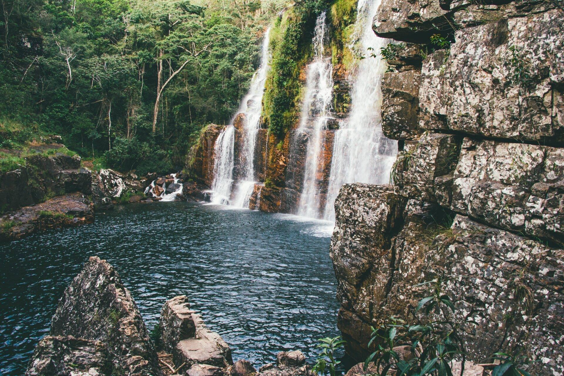 Spectacular waterfalls dropping into a turquoise pool surrounded by rocky cliffs and lush jungle