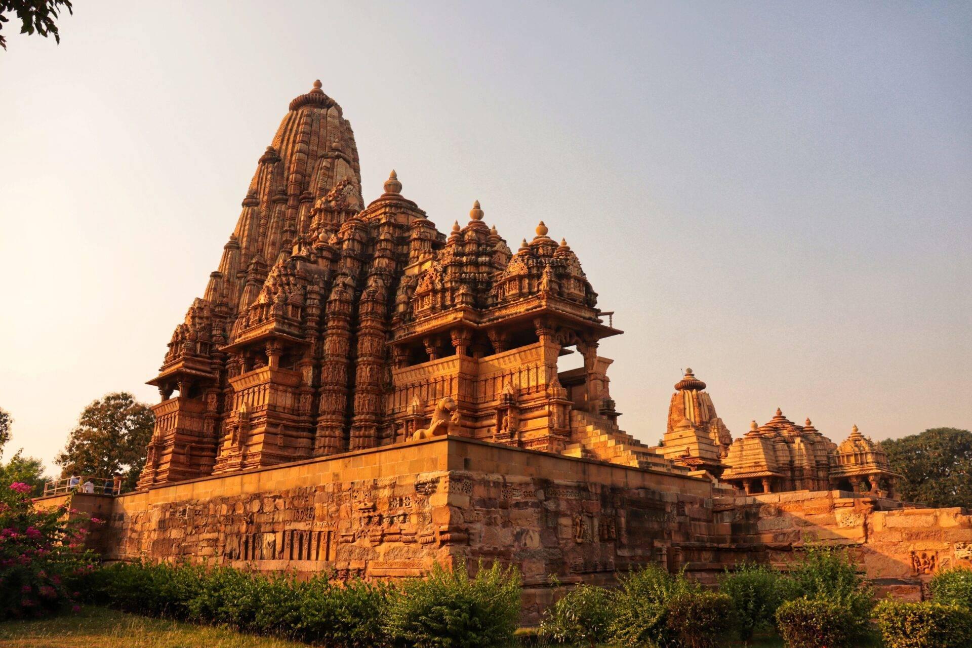 Red sandstone Hindu temple with ornate towers and detailed sculptures, bathed in sunset light