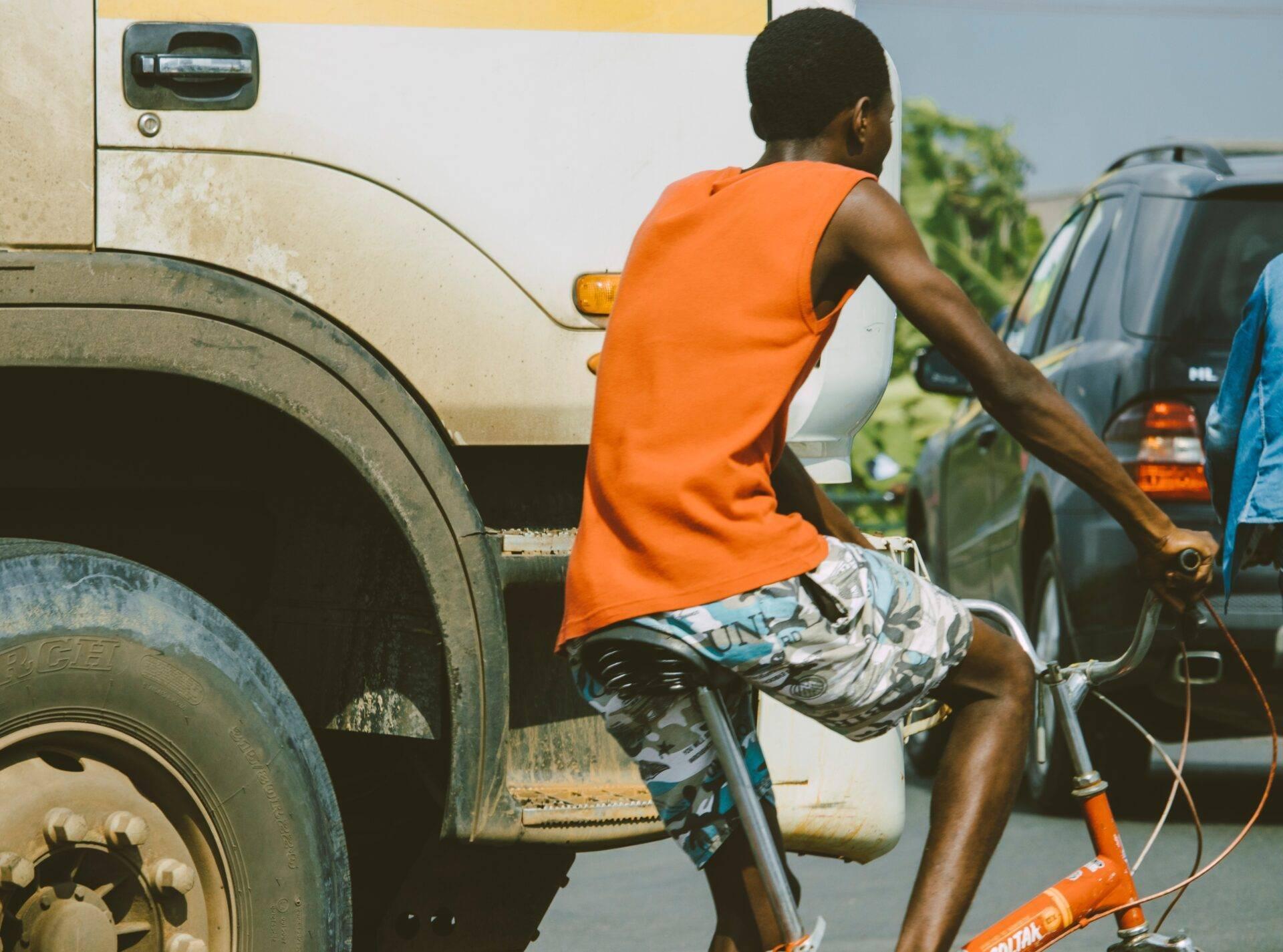 Un jeune homme en vélo devant un camion dans une rue animée d’Afrique de l’Ouest