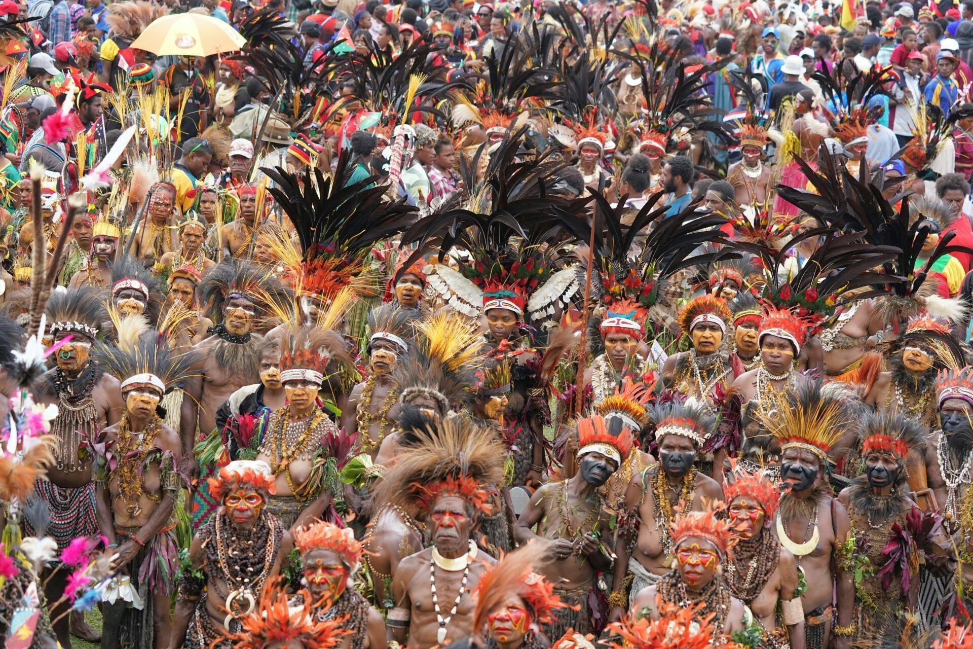 Foule dense de participants en costumes colorés avec plumes et peintures faciales à un festival culturel tropical