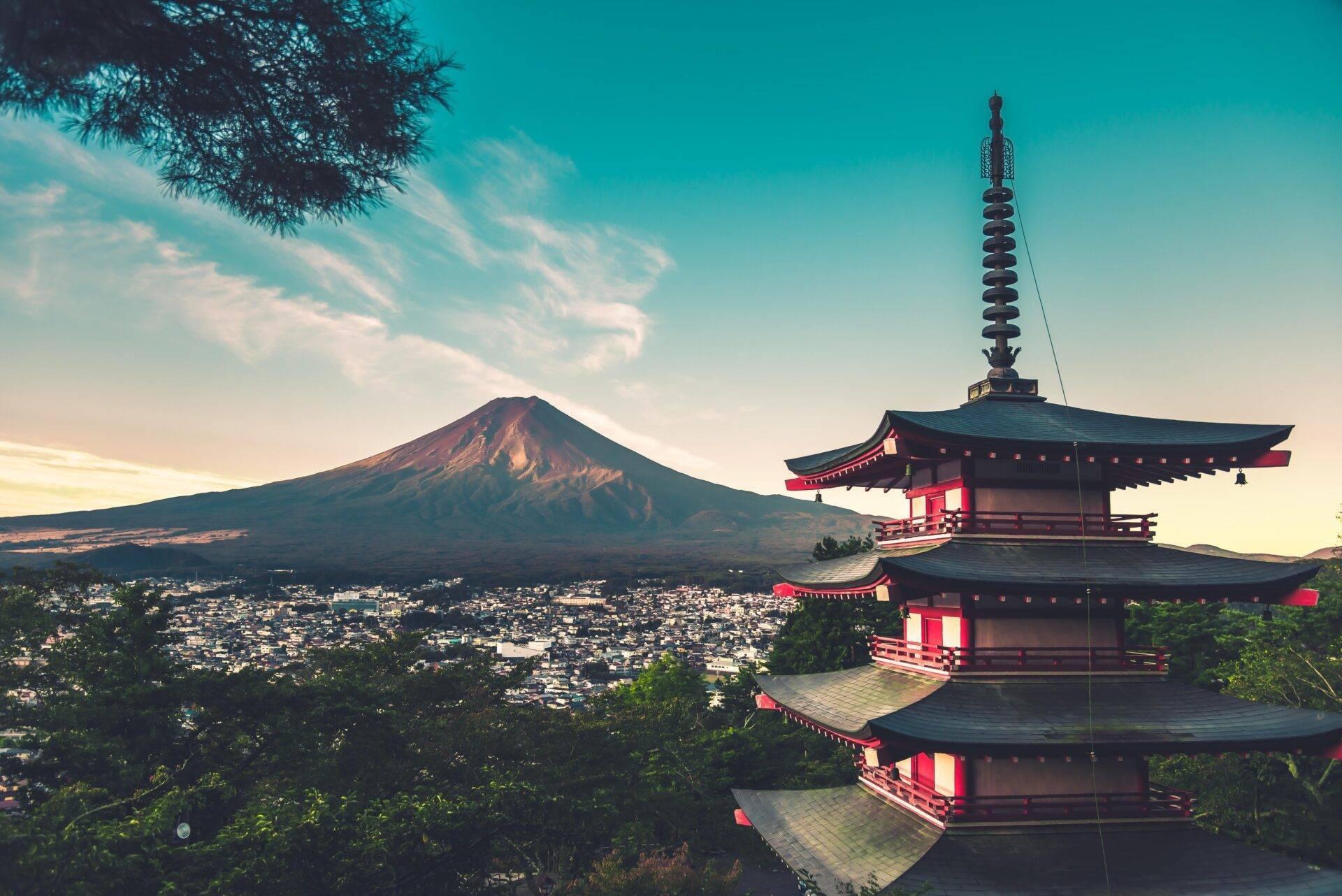 Panoramic view of Mount Fuji with a traditional Japanese red pagoda in the foreground and the city spreading below