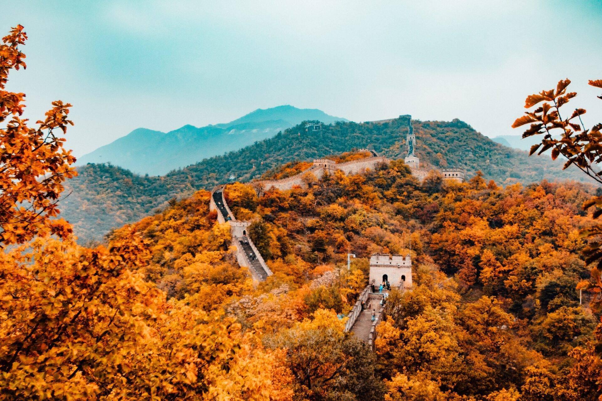 La Grande Muraille de Chine serpentant à travers des montagnes boisées aux teintes automnales dorées