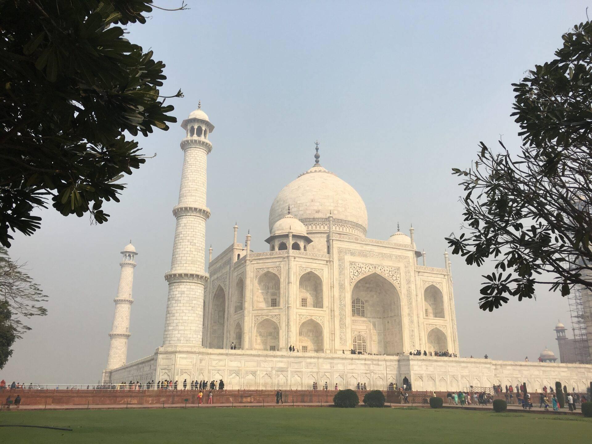 Iconic white domed monument with minarets, surrounded by visitors on a vast esplanade