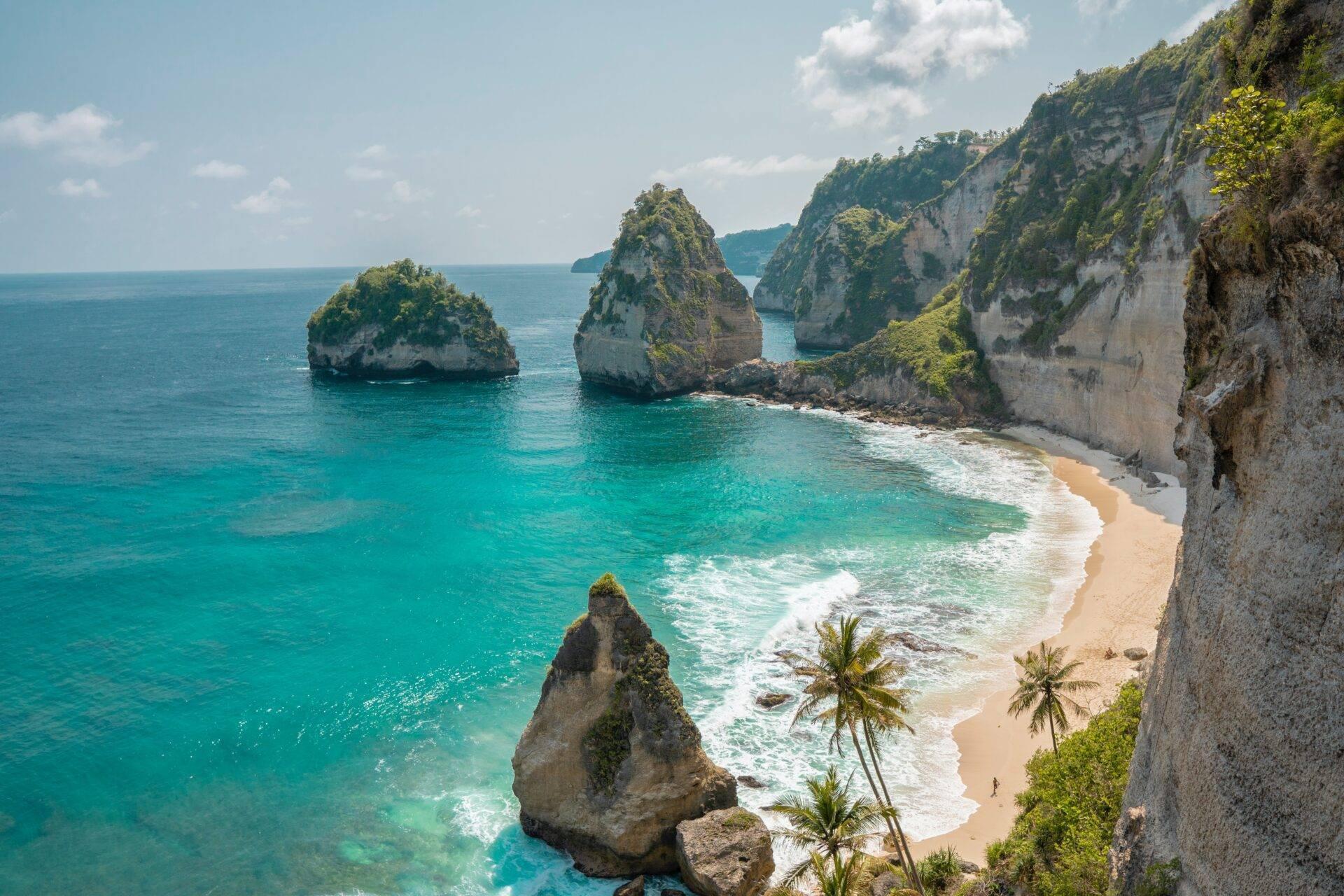 Tropical beach with white limestone cliffs, rocky islets and crystal-clear turquoise waters fringed by palm trees
