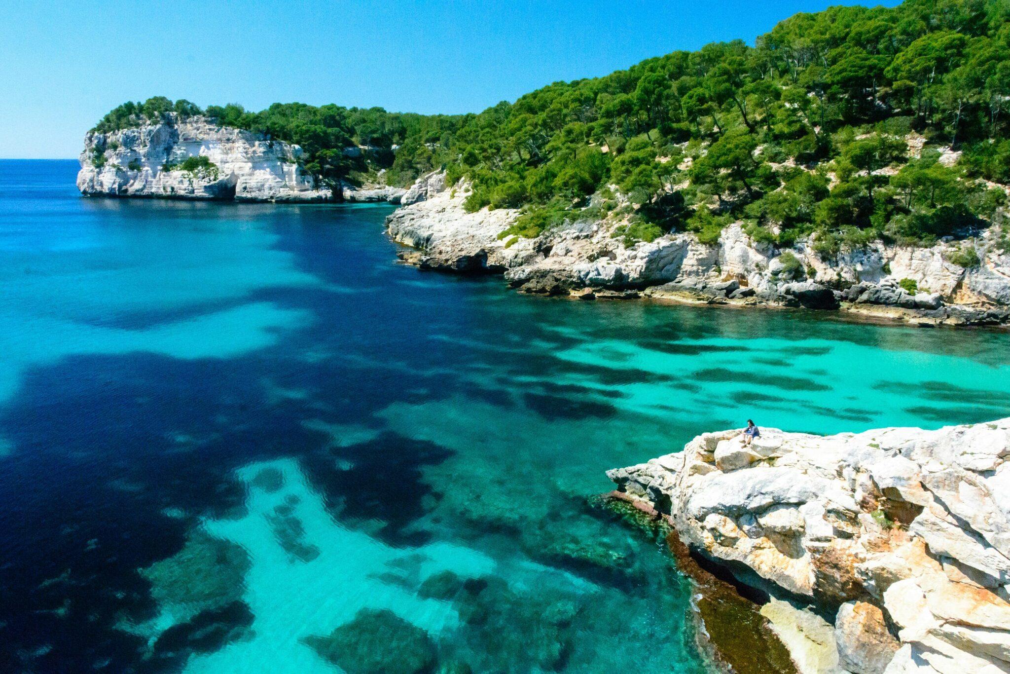 Crique méditerranéenne aux eaux turquoise cristallines, falaises calcaires blanches et végétation méditerranéenne verdoyante