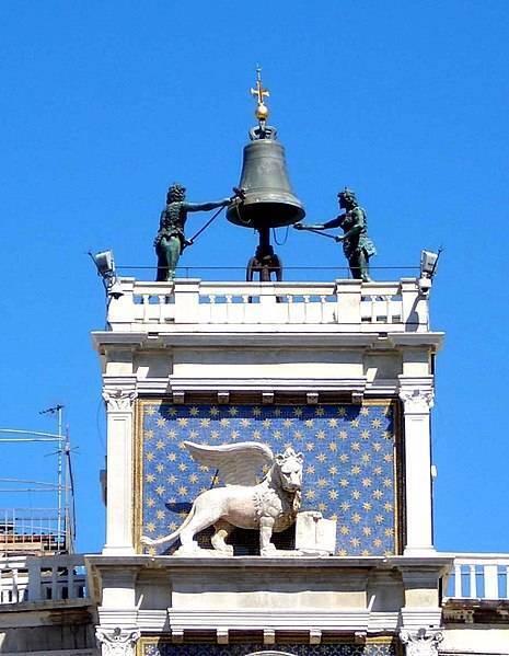 The Venetian Clock Tower with its star-studded face, bell and bronze sculptures against a blue sky