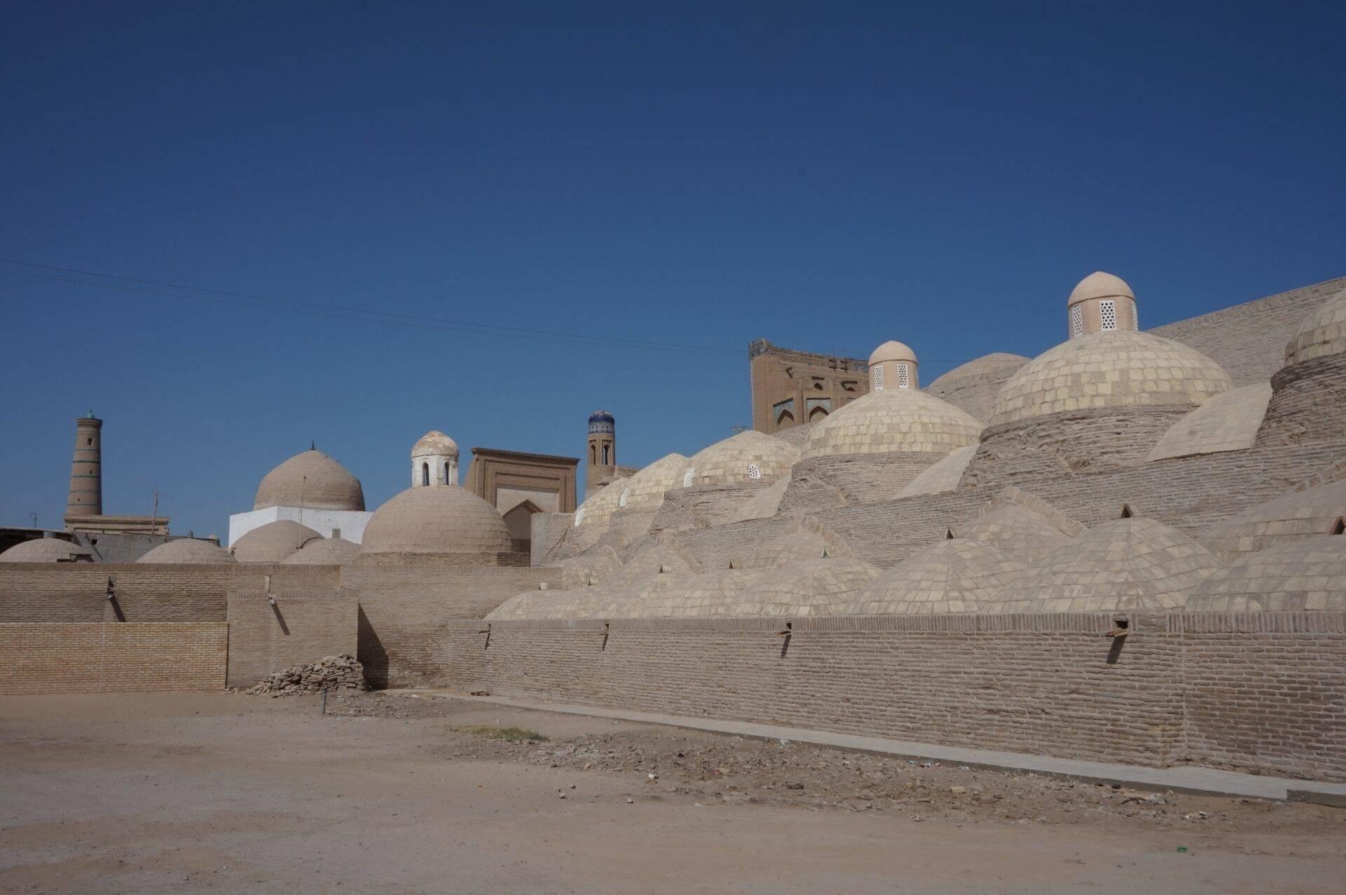 Panoramic view of a historic medina with whitewashed domes and brick ramparts under a clear blue sky