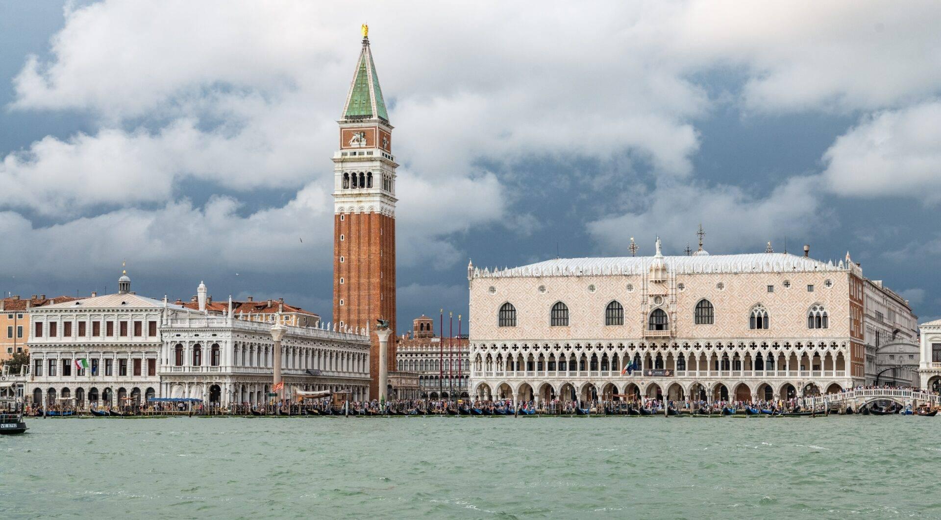 View from the Grand Canal towards St Mark’s Basilica and the Doge’s Palace with the Campanile bell tower under a cloudy sky