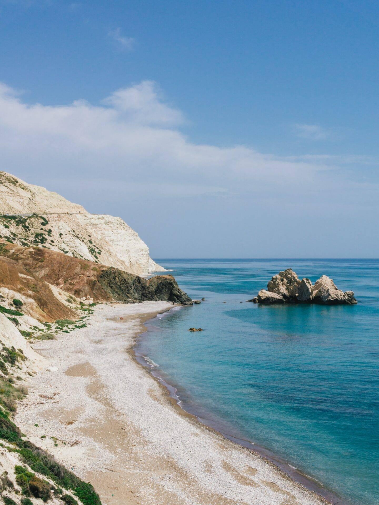 A beach of brilliant white pebbles framed by limestone cliffs, facing crystal-clear turquoise Mediterranean waters