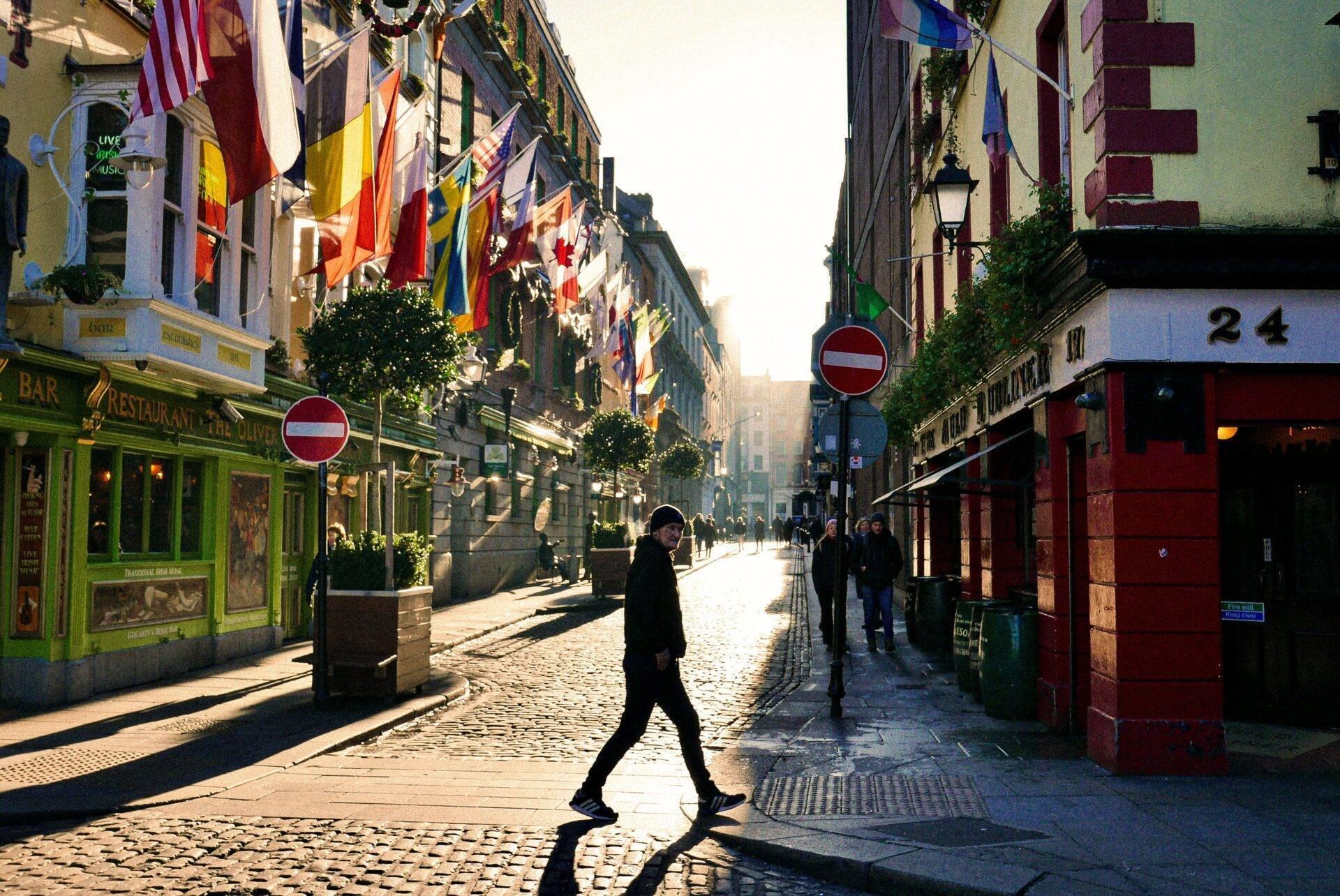 A cobbled European street with colourful bars, international flags and historic facades in natural daylight