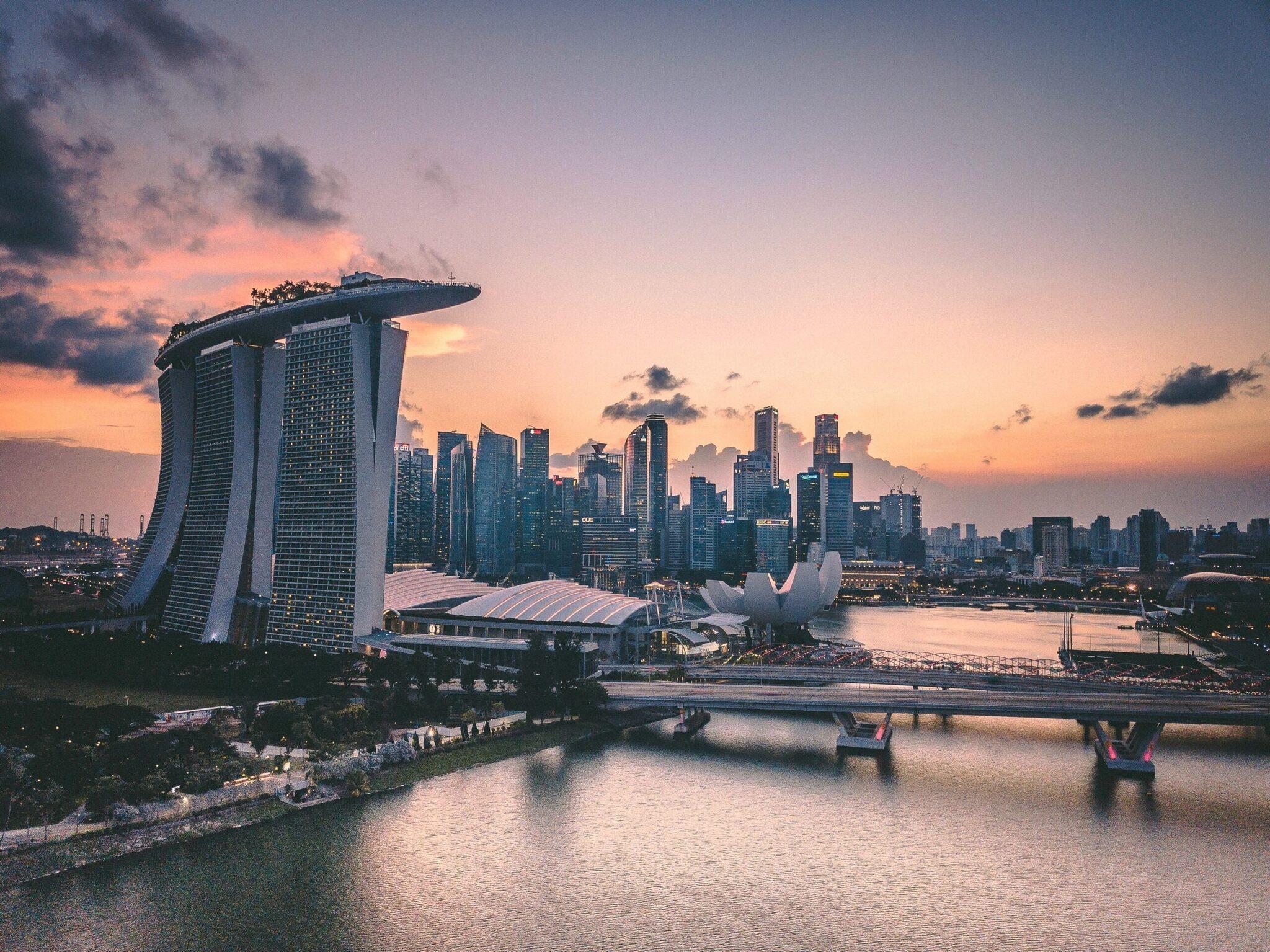 Skyline urbain au coucher de soleil avec gratte-ciels modernes et bâtiment futuriste en forme de voile au bord de l’eau