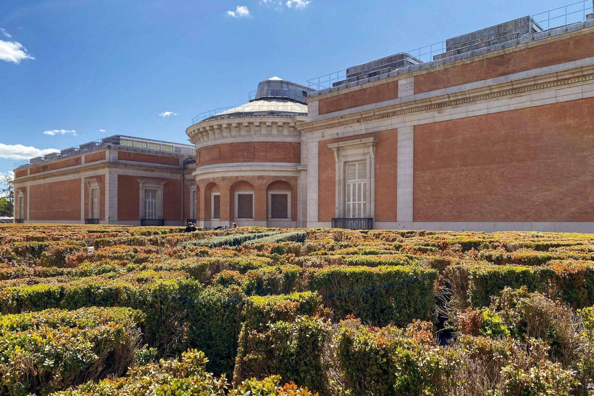 Musée en briques rouges avec dôme vitré entouré de jardins fleuris jaunes en terrasses
