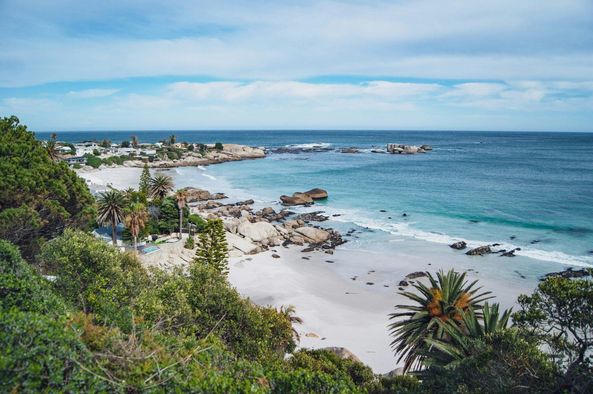 Aerial view of a white-sand beach bordered by granite rocks and Mediterranean coastal vegetation