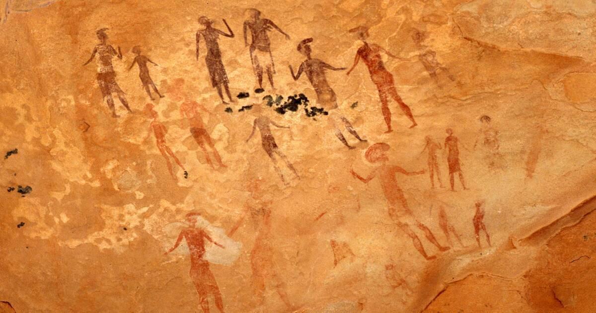 Peintures rupestres anciennes représentant des silhouettes humaines en ocre sur une paroi rocheuse désertique