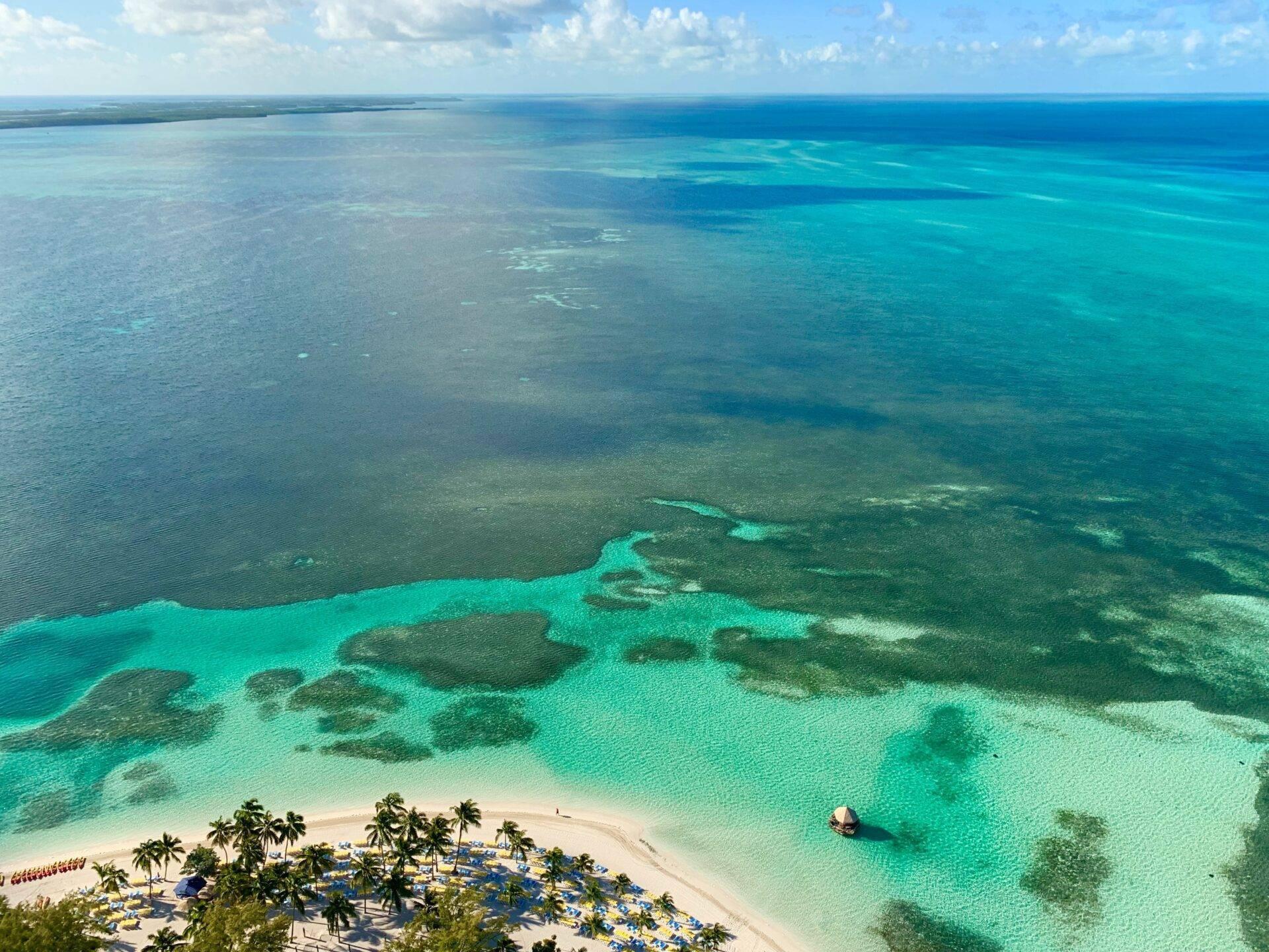 Vue aérienne d’une plage paradisiaque aux eaux turquoise bordée de palmiers et d’îlots boisés
