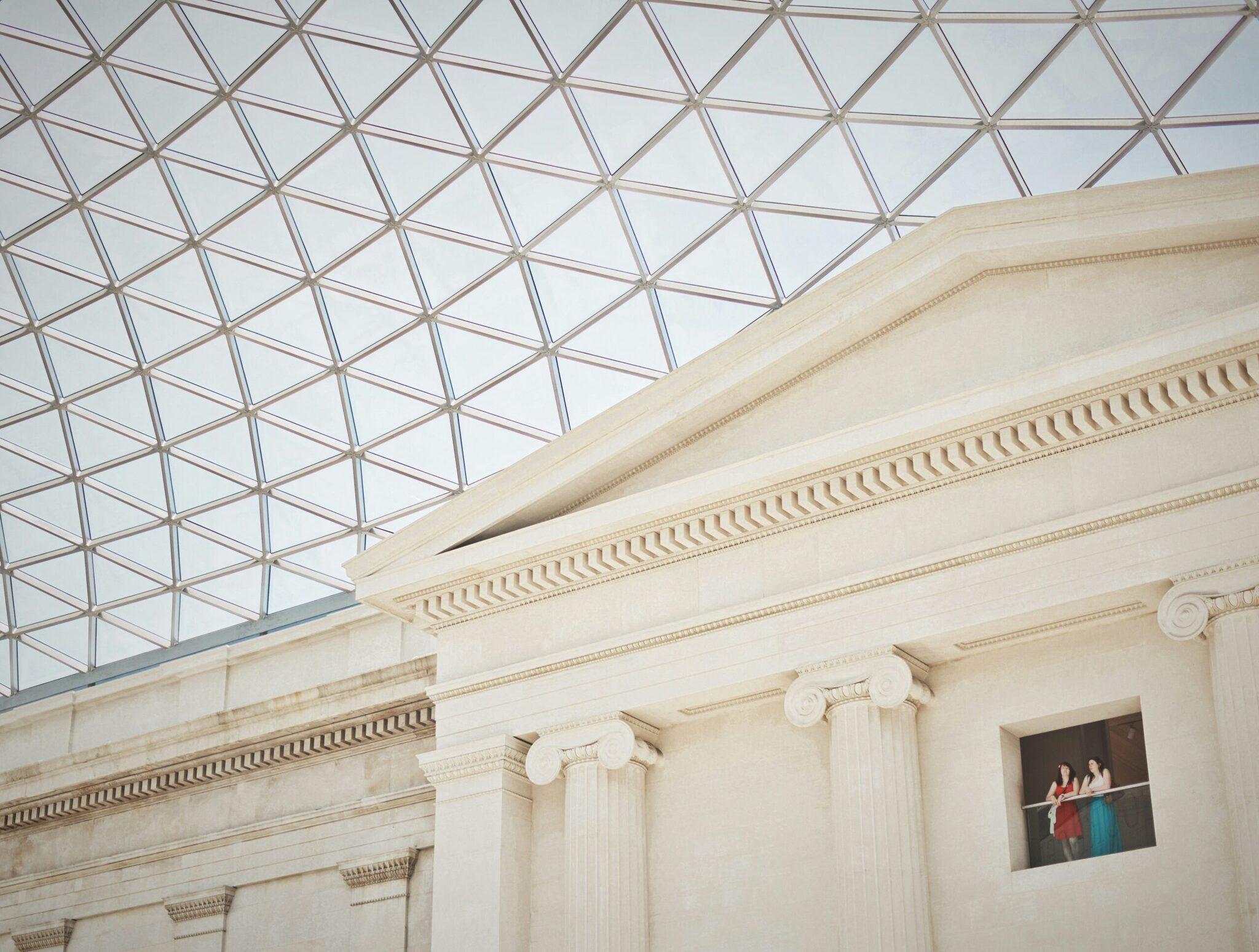 Intérieur de musée avec plafond géométrique vitré et colonnes classiques ornées de chapiteaux