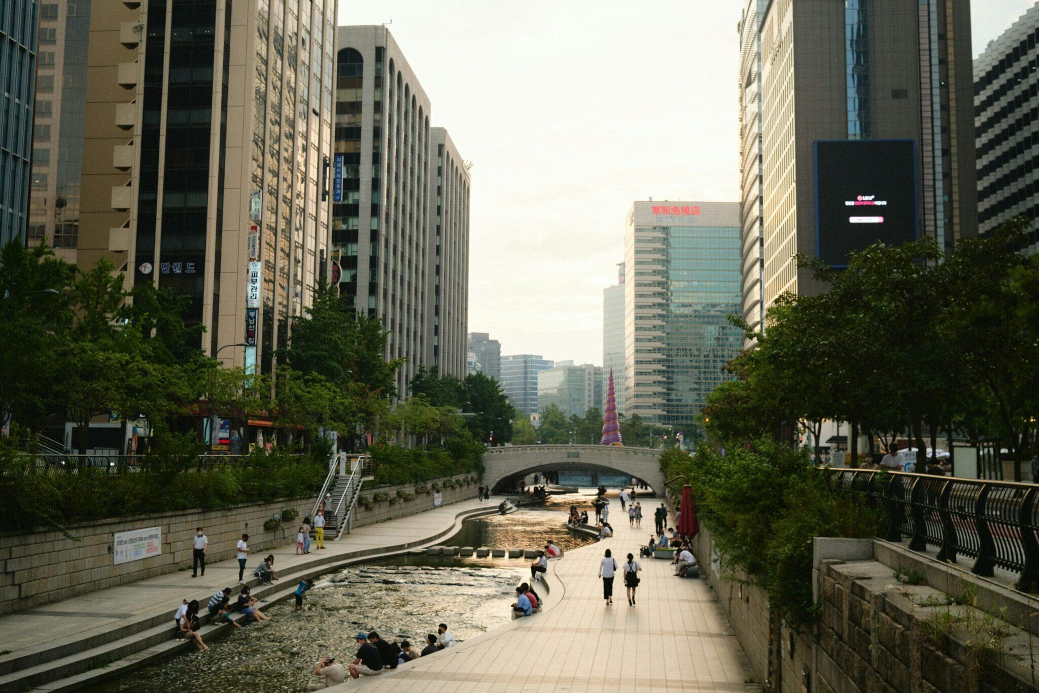 Urban park with a landscaped stream, modern buildings and passers-by in a vibrant Asian metropolis