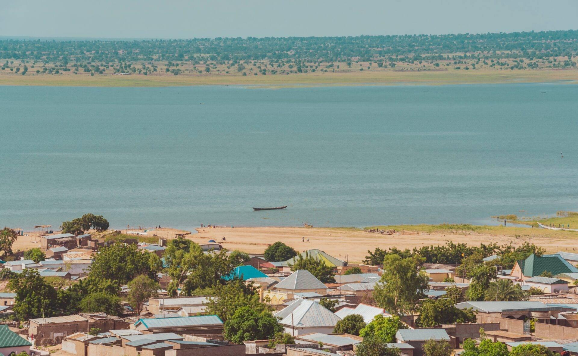 Vue aérienne d’une ville côtière avec plage, maisons colorées et grand lac ou mer turquoise en arrière-plan