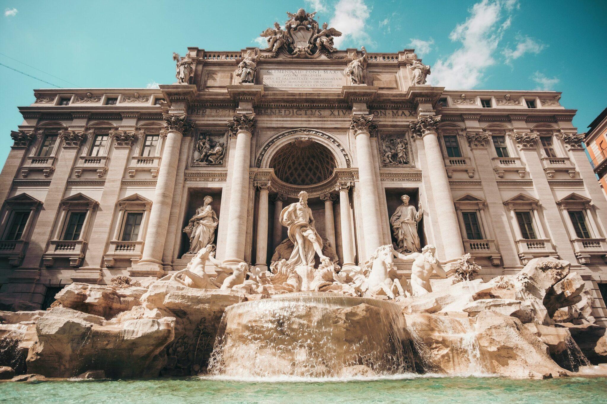 The Trevi Fountain with its majestic baroque facade, sculptures and turquoise basin under a clear sky