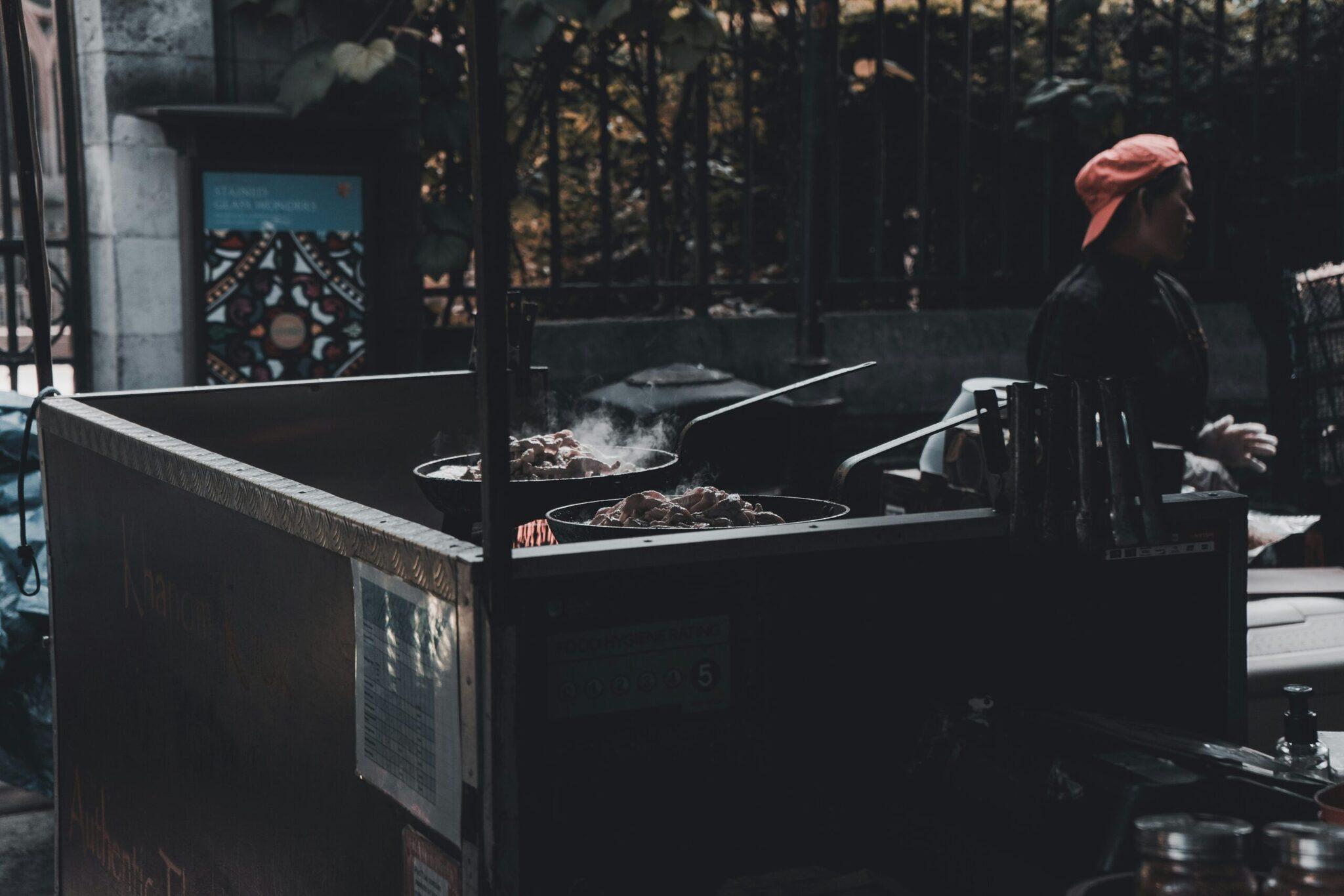 Un vendeur de street food prépare des plats dans des woks dans une ruelle urbaine asiatique animée