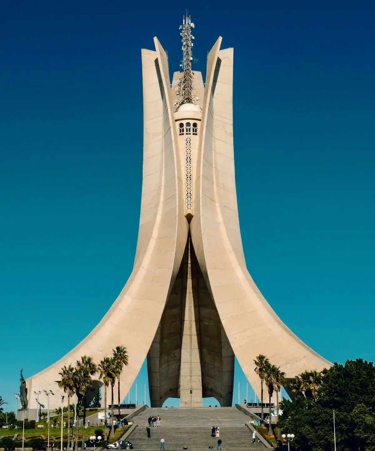 Un monument moderne blanc aux formes géométriques imposantes avec une tour centrale, sous un ciel bleu dégagé