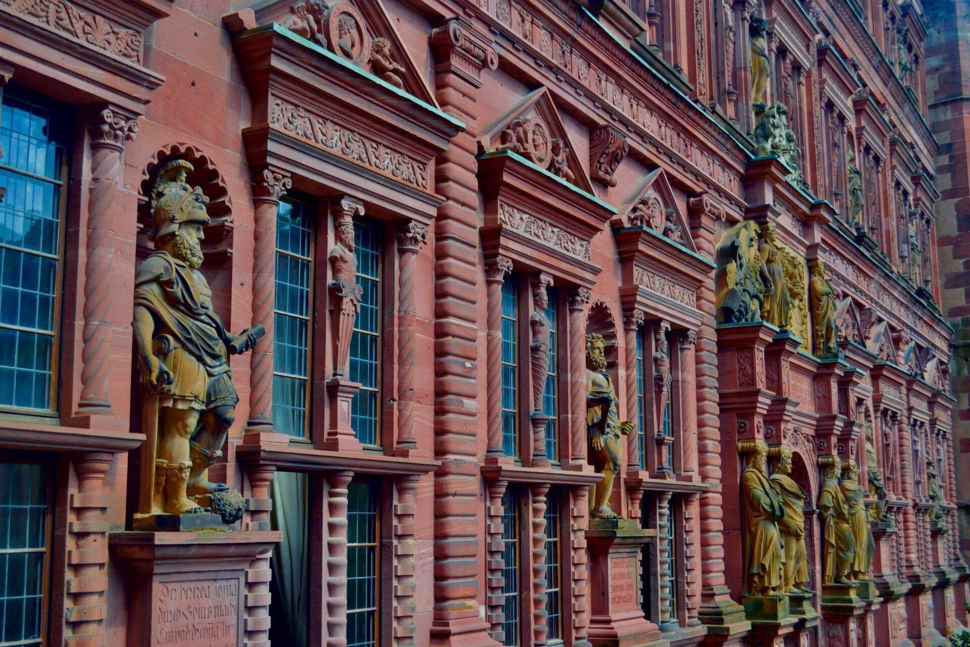 Ornate red brick facade with gilded statues and sculpted columns, historic German architecture