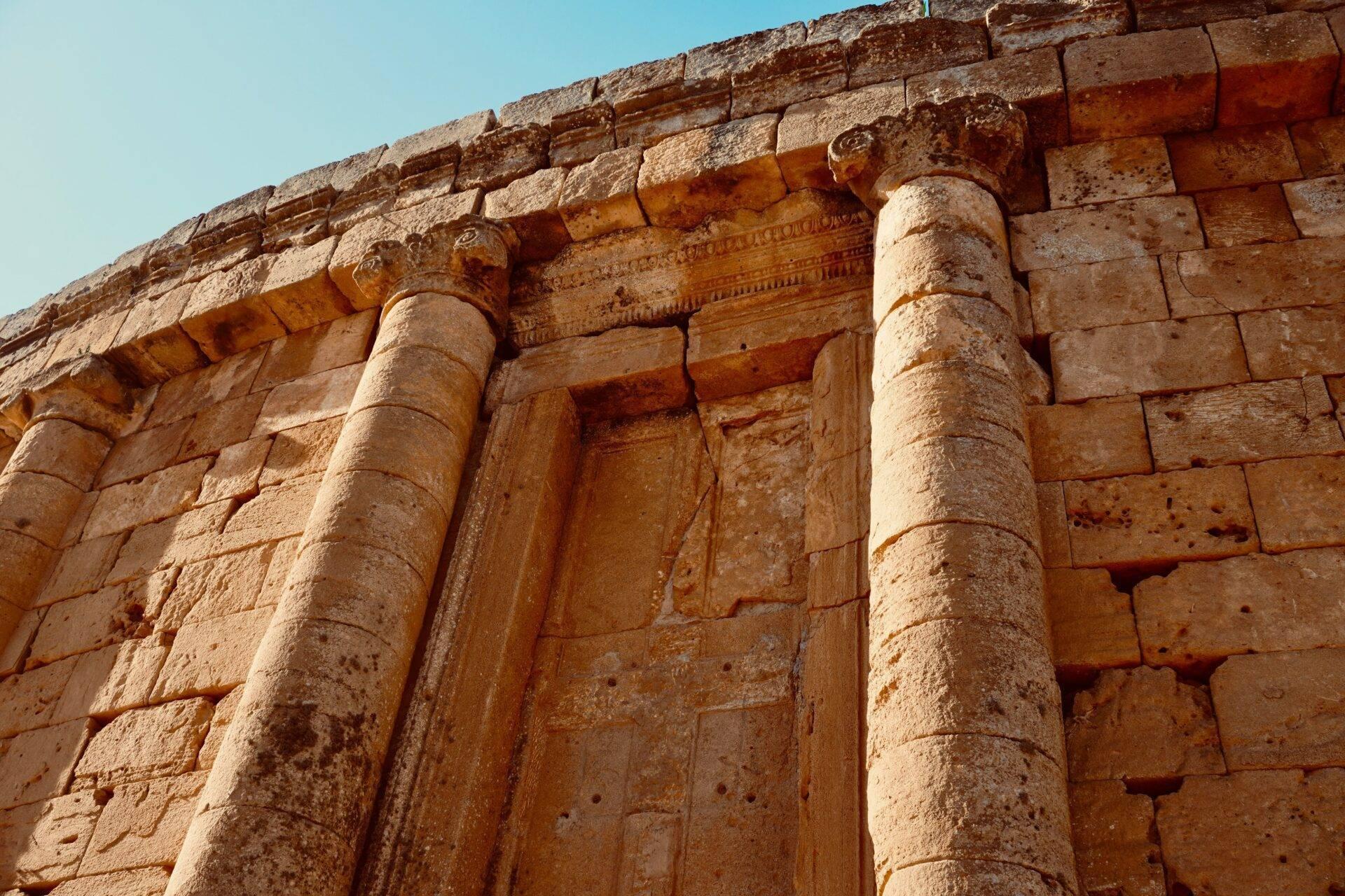 Architectural detail of an ancient stone temple with fluted columns and sculpted decorative friezes