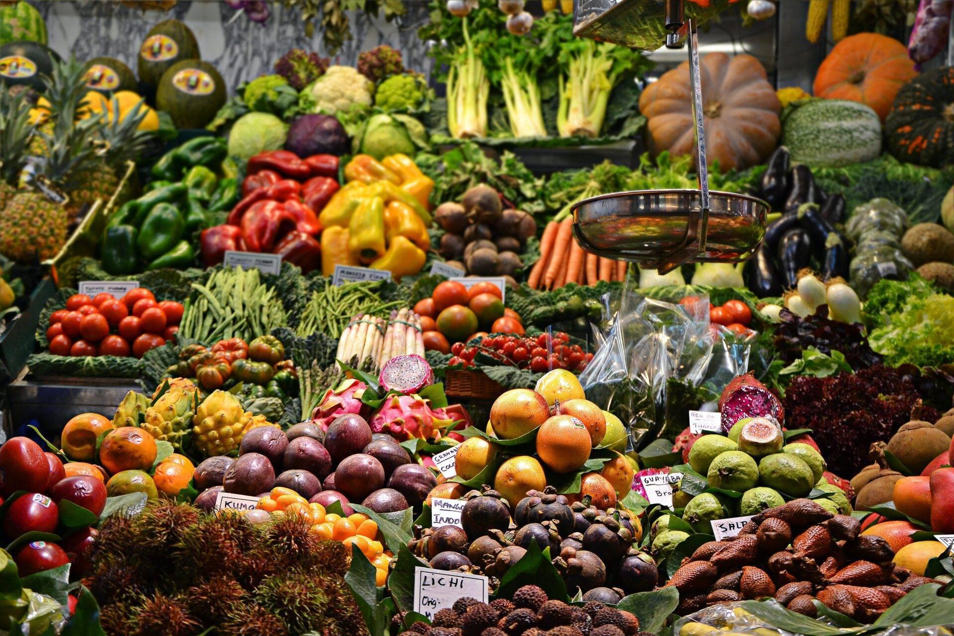 Étal coloré de marché tropical avec fruits et légumes frais variés, eau versée en arrière-plan