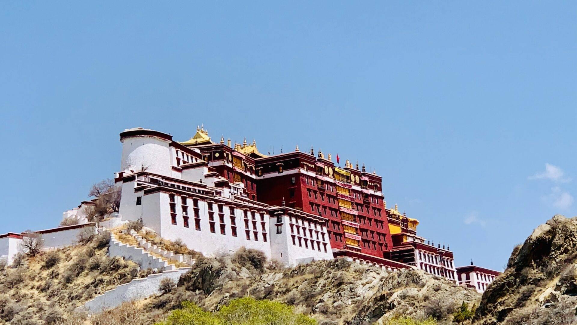 Un monastère bouddhiste himalayen aux murs blancs et toitures dorées perché sur une montagne rocheuse