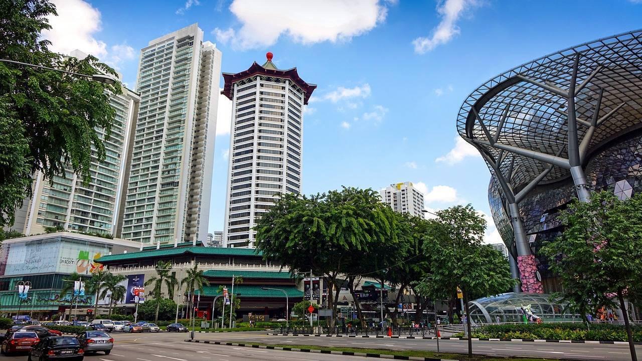 Une rue commerçante urbaine avec immeubles modernes, temple asiatique et structure architecturale contemporaine sous un ciel dégagé