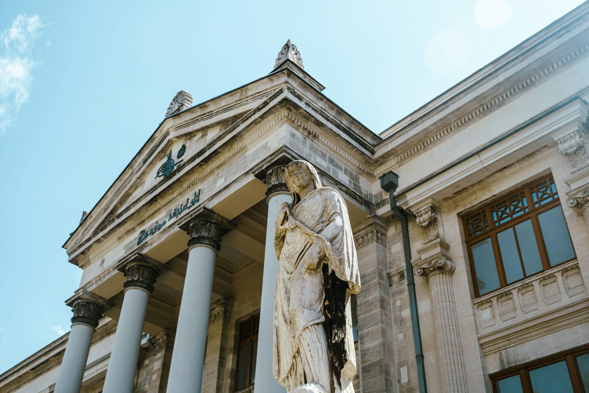 Façade néoclassique d’un musée avec colonnes corinthiennes et statue d’ange blanc sous ciel bleu