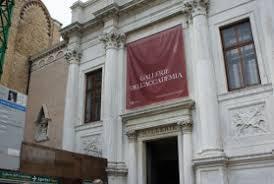 White facade of a historic Venetian building with a red banner and classical architectural details